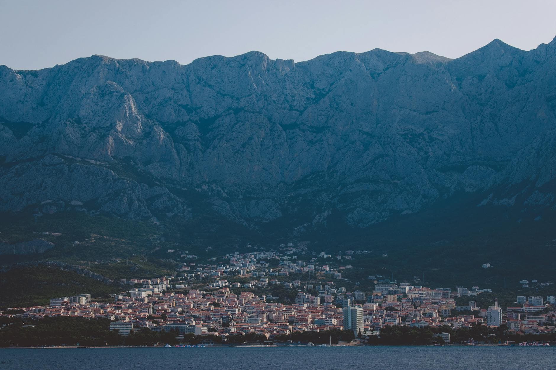 A breathtaking view of Makarska city nestled against a majestic mountain range by the sea.