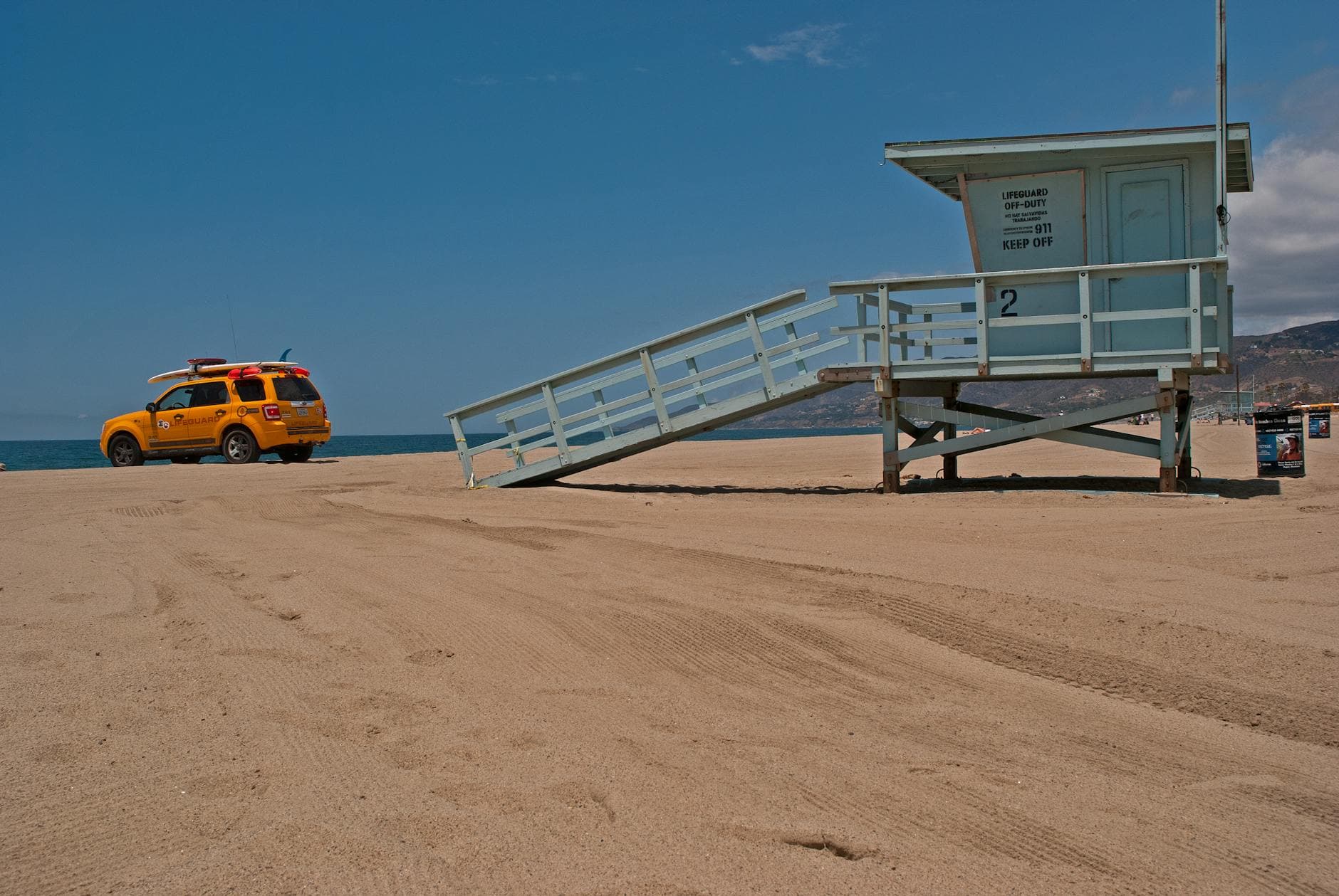 Lifeguard tower and rescue vehicle on a sunny California beach, perfect for summer safety.
