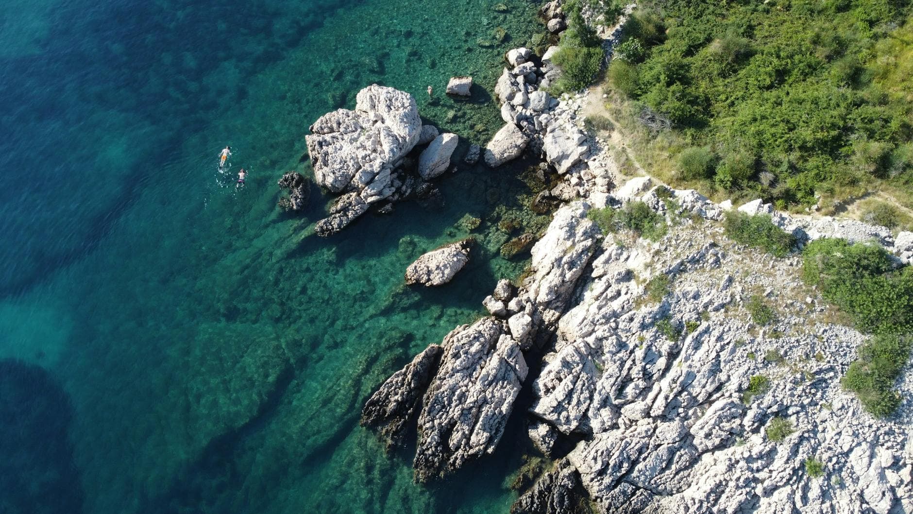 Explore the stunning aerial view of the rocky coastline and clear waters in Malinska, Croatia.