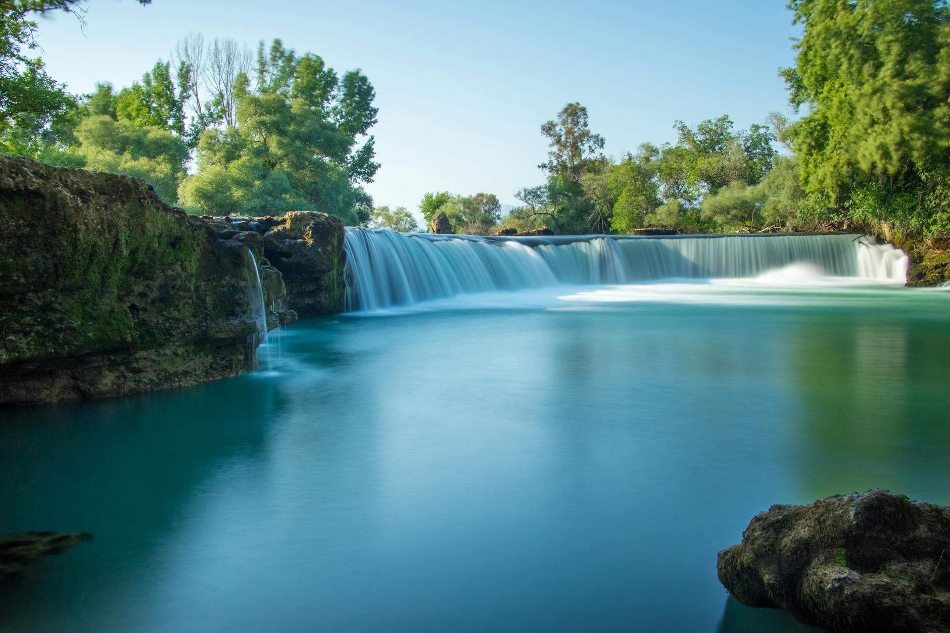 Peaceful view of the Manavgat Waterfall surrounded by lush greenery in Turkey.