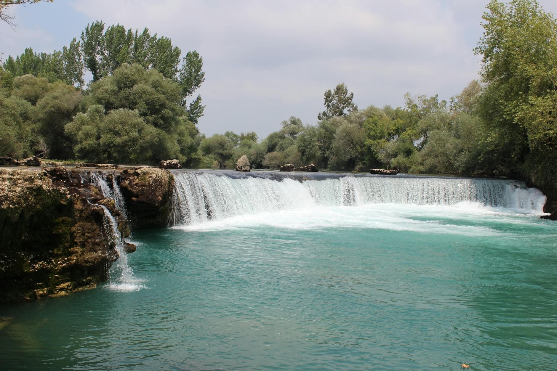 Serene view of Manavgat Waterfalls surrounded by lush greenery in Antalya, Turkey.