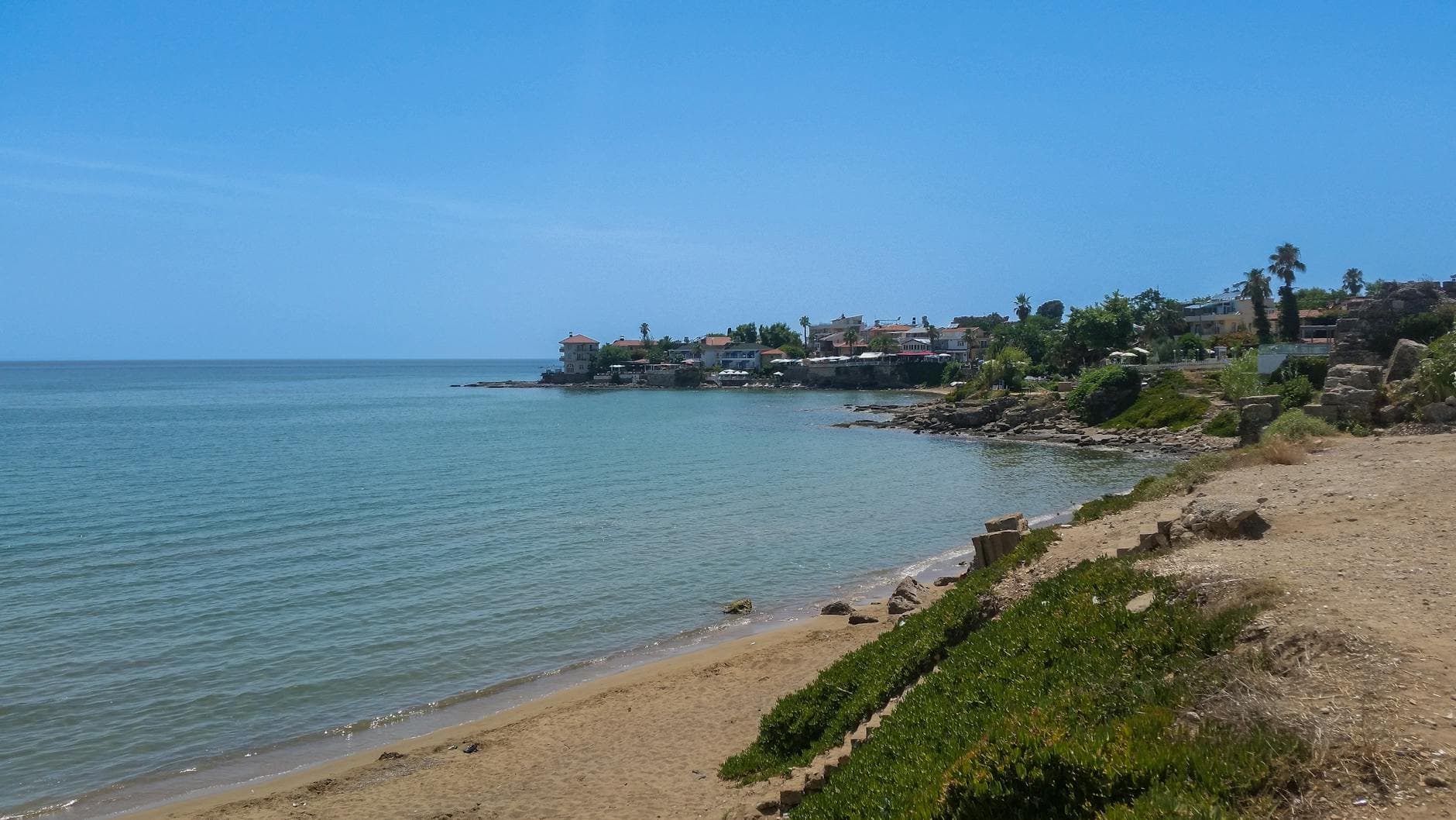 Serene beach view in Side, Antalya, Türkiye, showcasing tranquil waters and a clear sky.