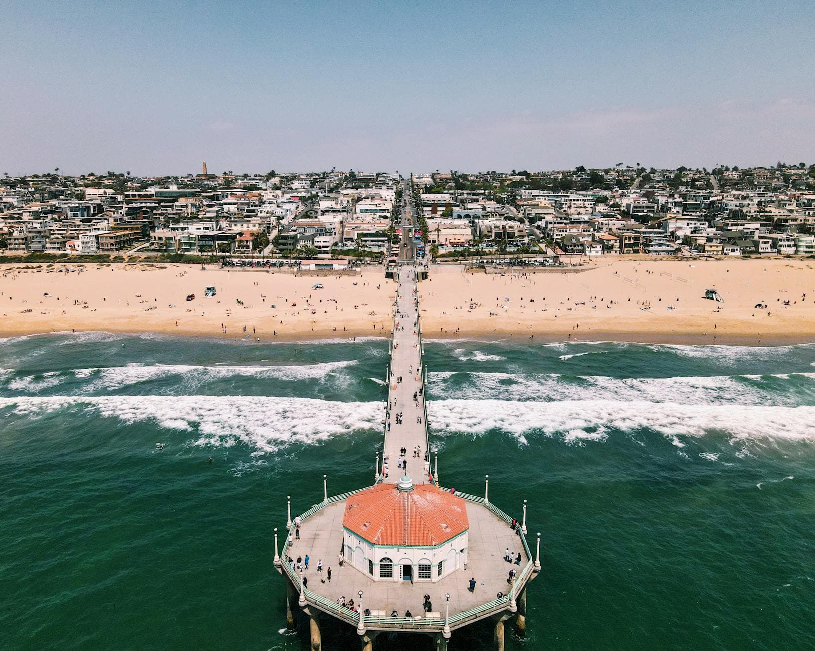 Stunning aerial shot of Manhattan Beach Pier extending into the ocean with vibrant city backdrop.