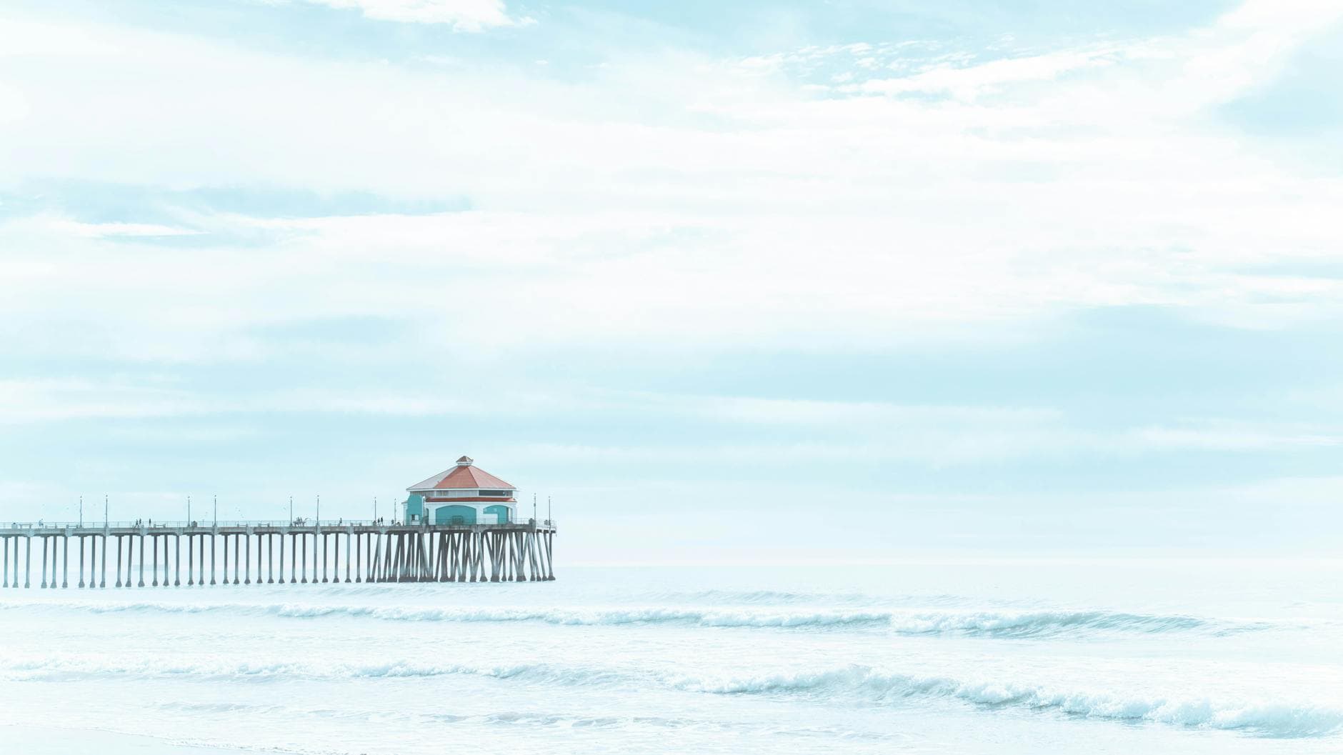A tranquil view of Manhattan Beach Pier with gentle waves and a serene blue sky.
