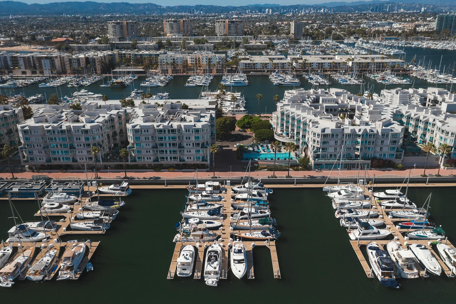 Stunning aerial view of a marina with docked yachts and nearby residential buildings, creating a picturesque coastal scene.