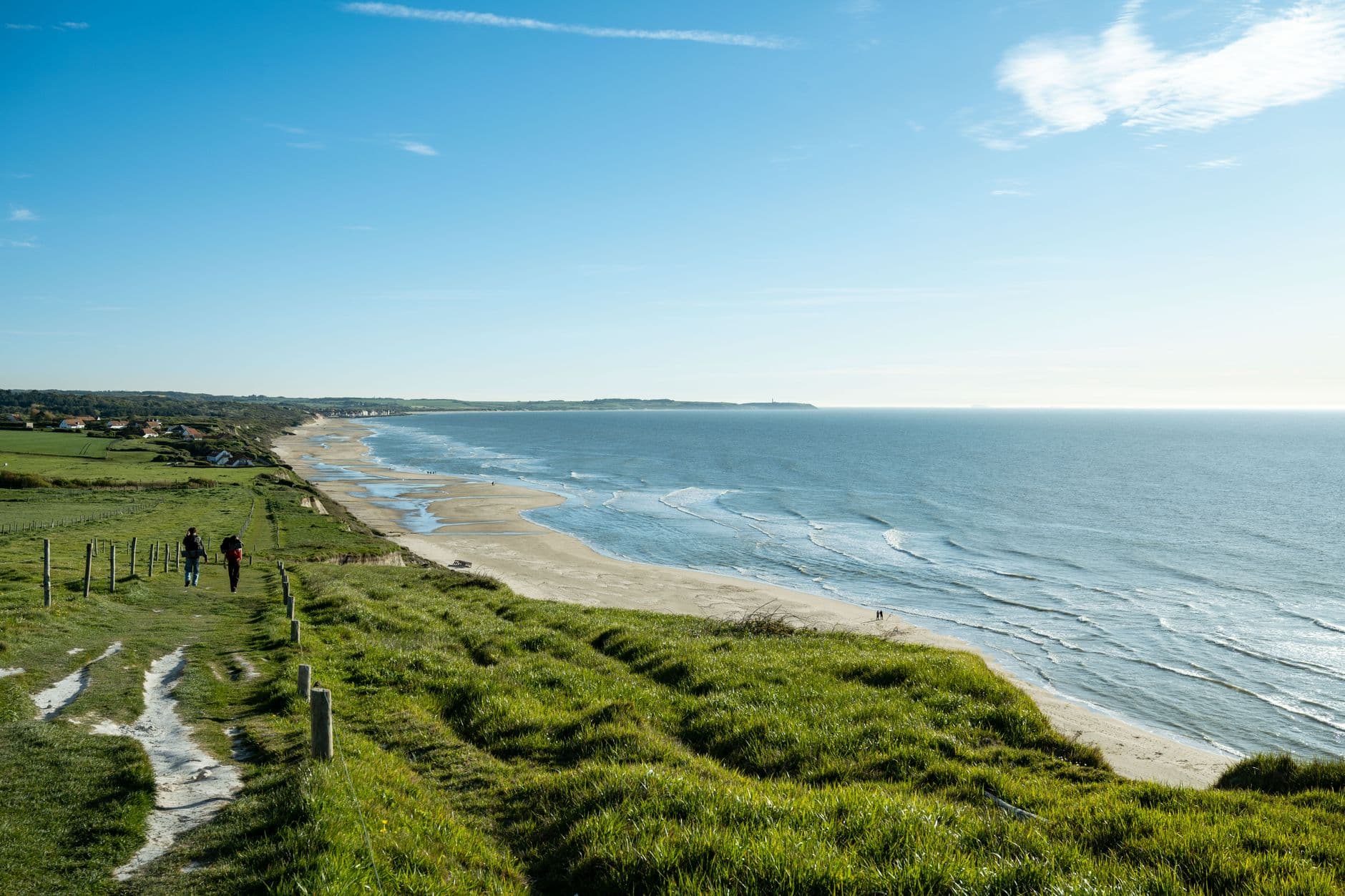 Picturesque view of a coastal pathway leading to the sea at Escalles, France, under clear blue skies.