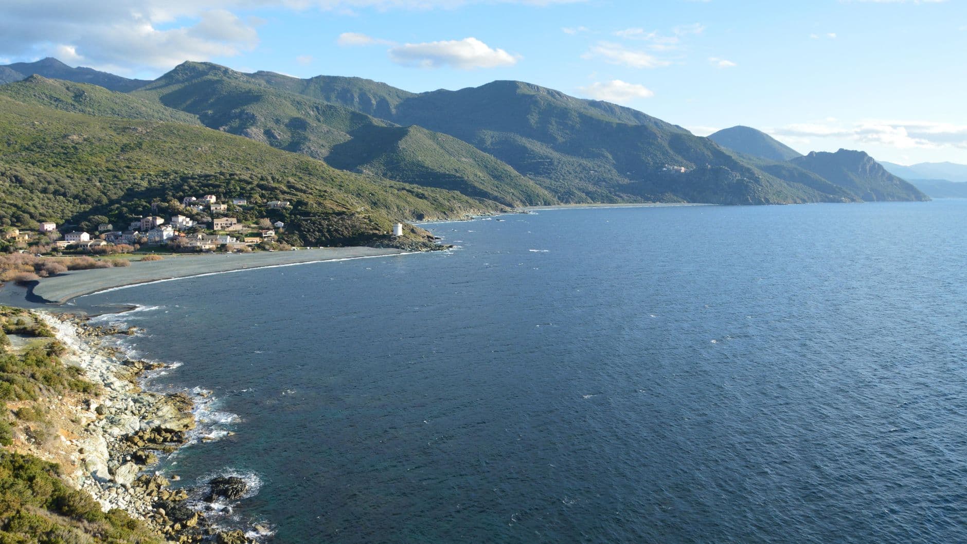 Beautiful aerial view of Ogliastro's coastline in Corse, France, featuring the lush mountains and blue sea.