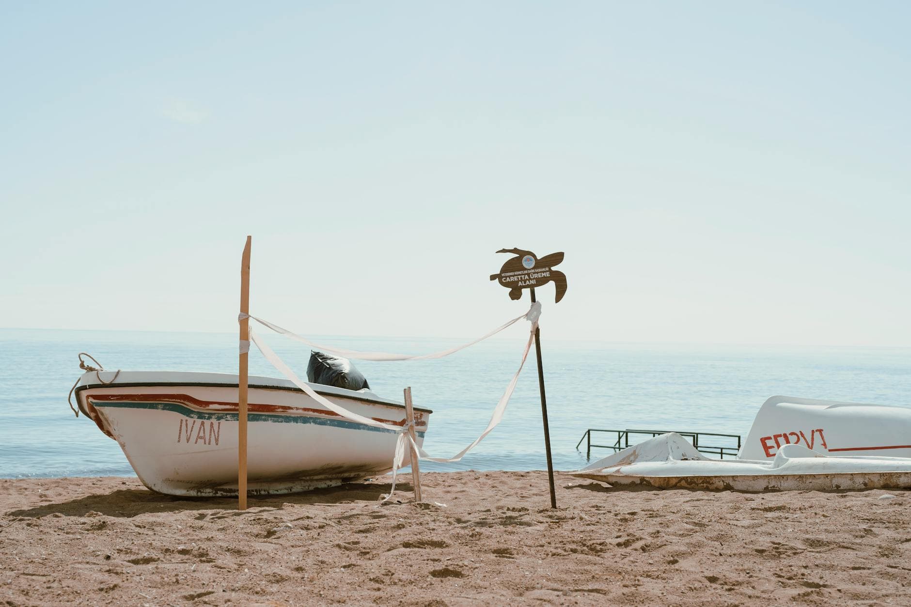 Scenic view of boats on a sandy beach in Mersin, Turkey, under a clear blue sky.