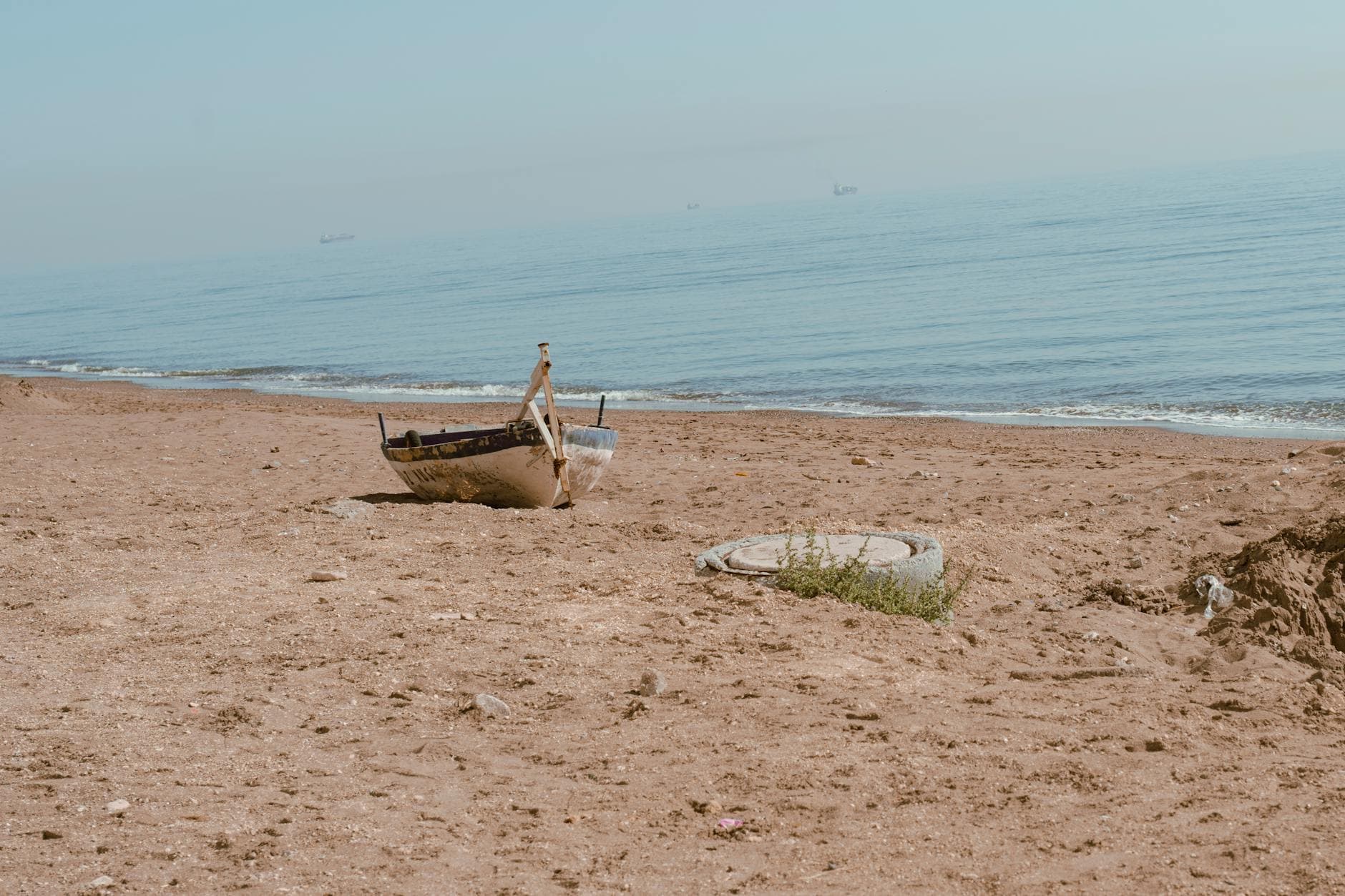 A solitary abandoned boat on the sandy shores of Mersin, Turkey, under clear skies.