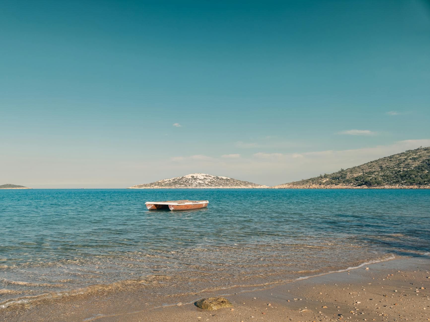 Enjoy a serene view of a boat on the calm turquoise waters of Mersin, Türkiye.