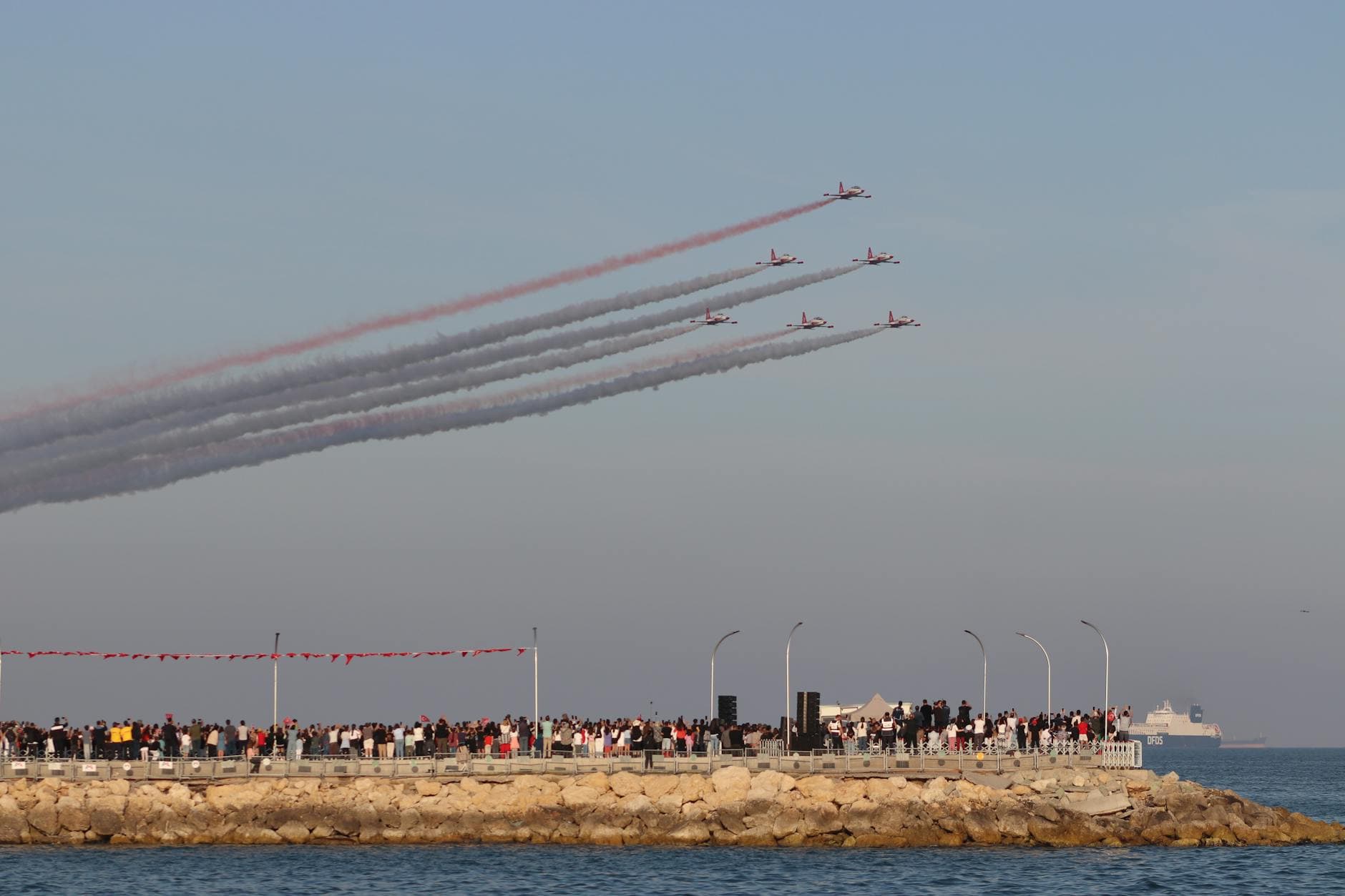 Turkish Stars perform stunning aerial acrobatics over the Mersin seafront with a clear sky.