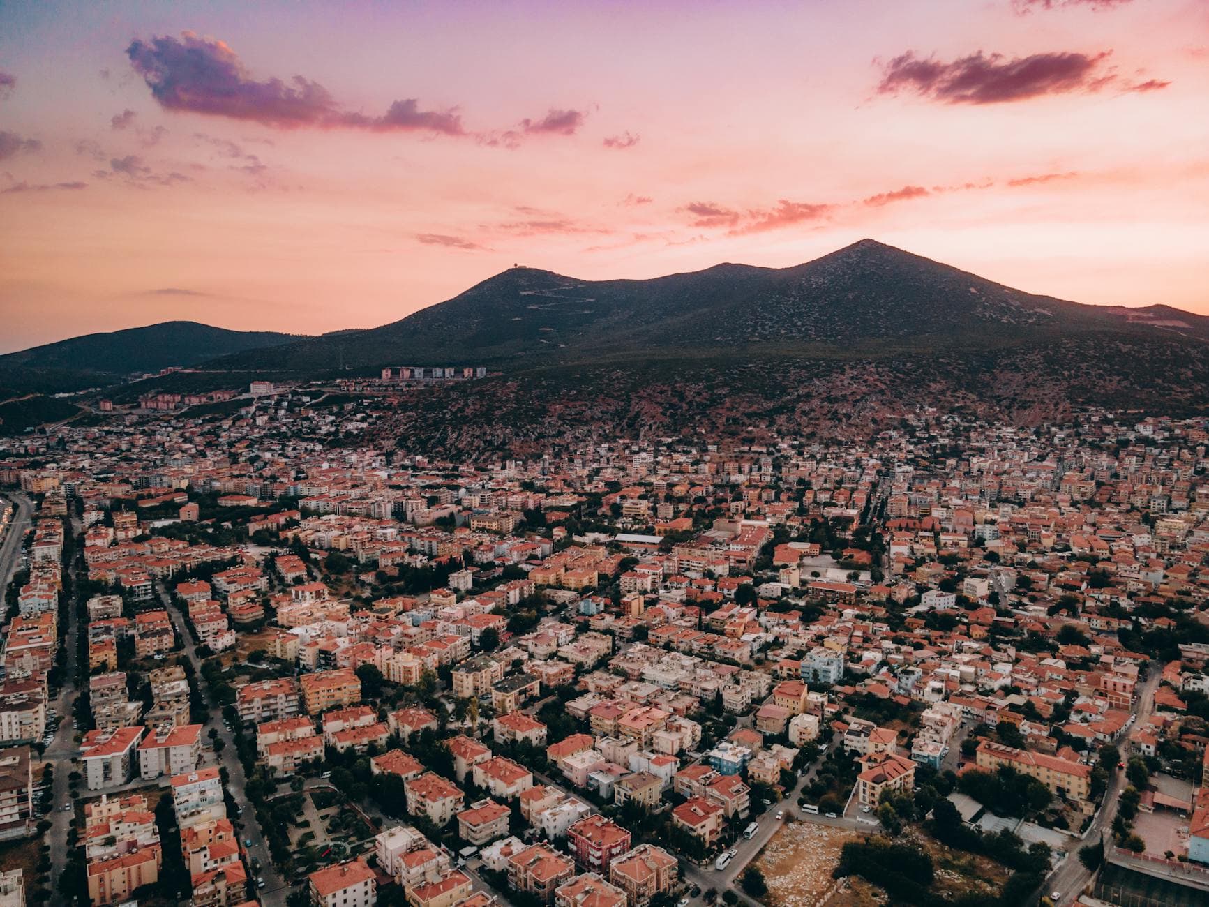 A stunning aerial view of Milas, Turkey, showcasing a vibrant residential area against a beautiful sunset sky.