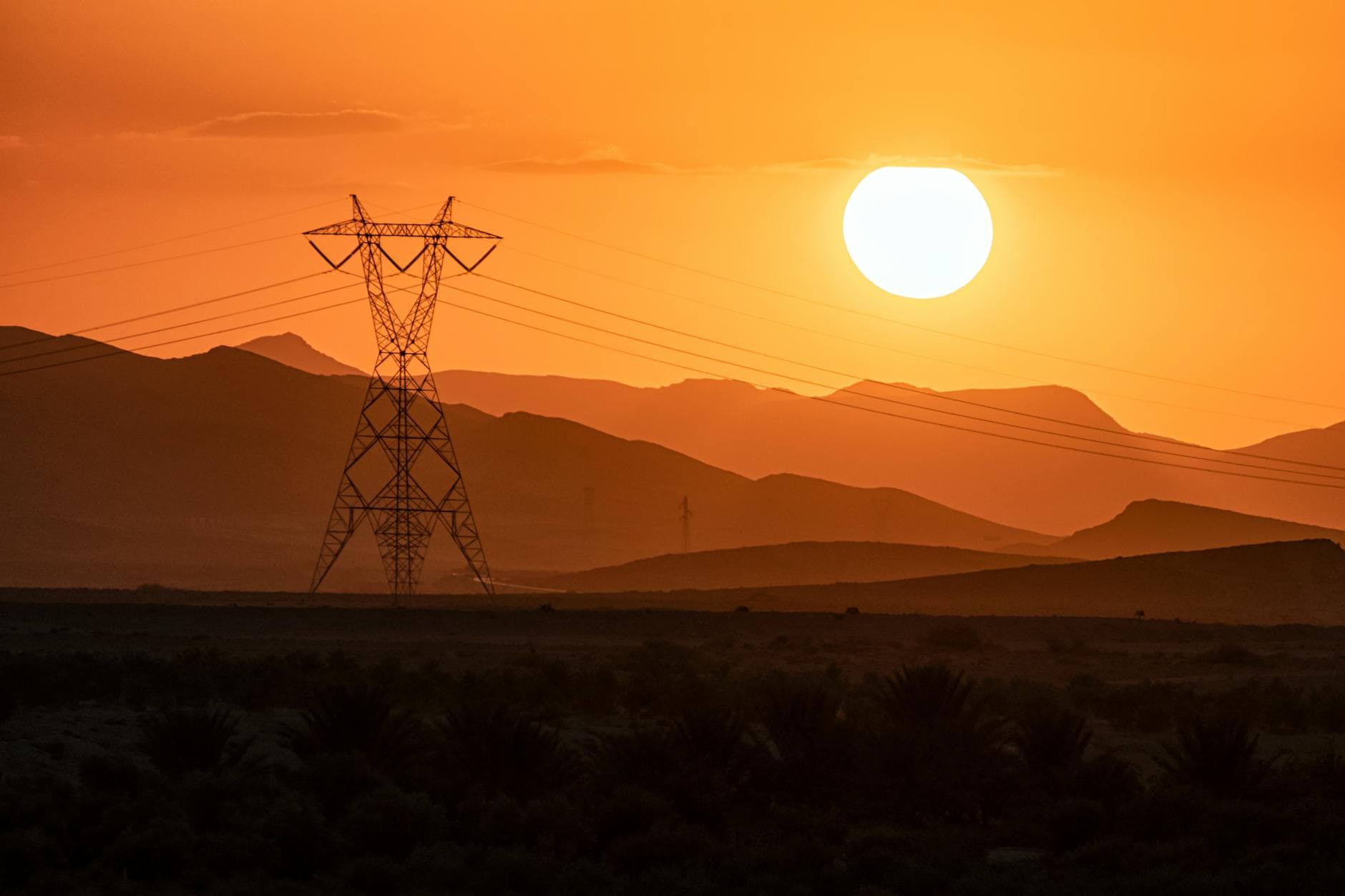 Scenic view of sunset with transmission tower against silhouetted mountains in Mila, Algeria.