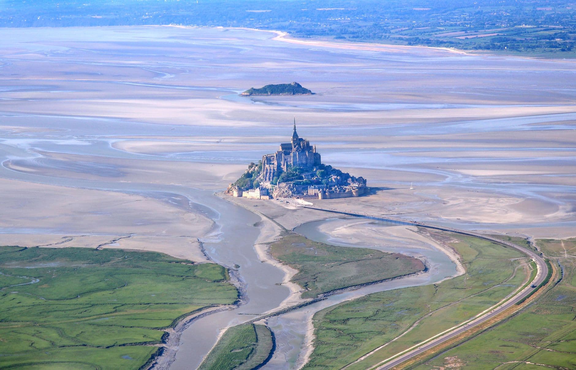 Stunning aerial shot of Mont Saint-Michel in Normandie, France during low tide with expansive views of the surrounding bay.