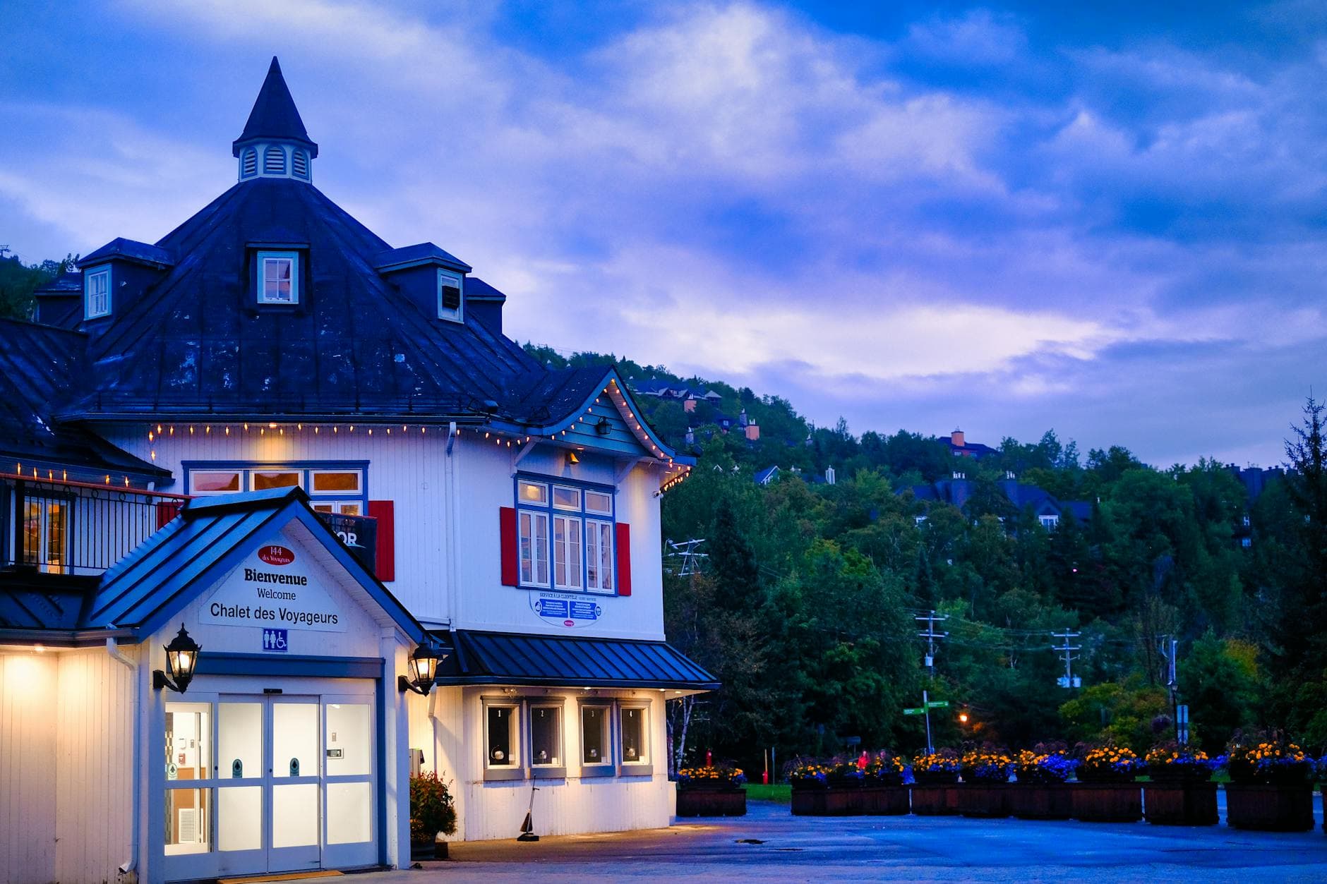 Beautiful evening view of Chalet des Voyageurs in Mont Tremblant with vibrant skies and lush greenery.