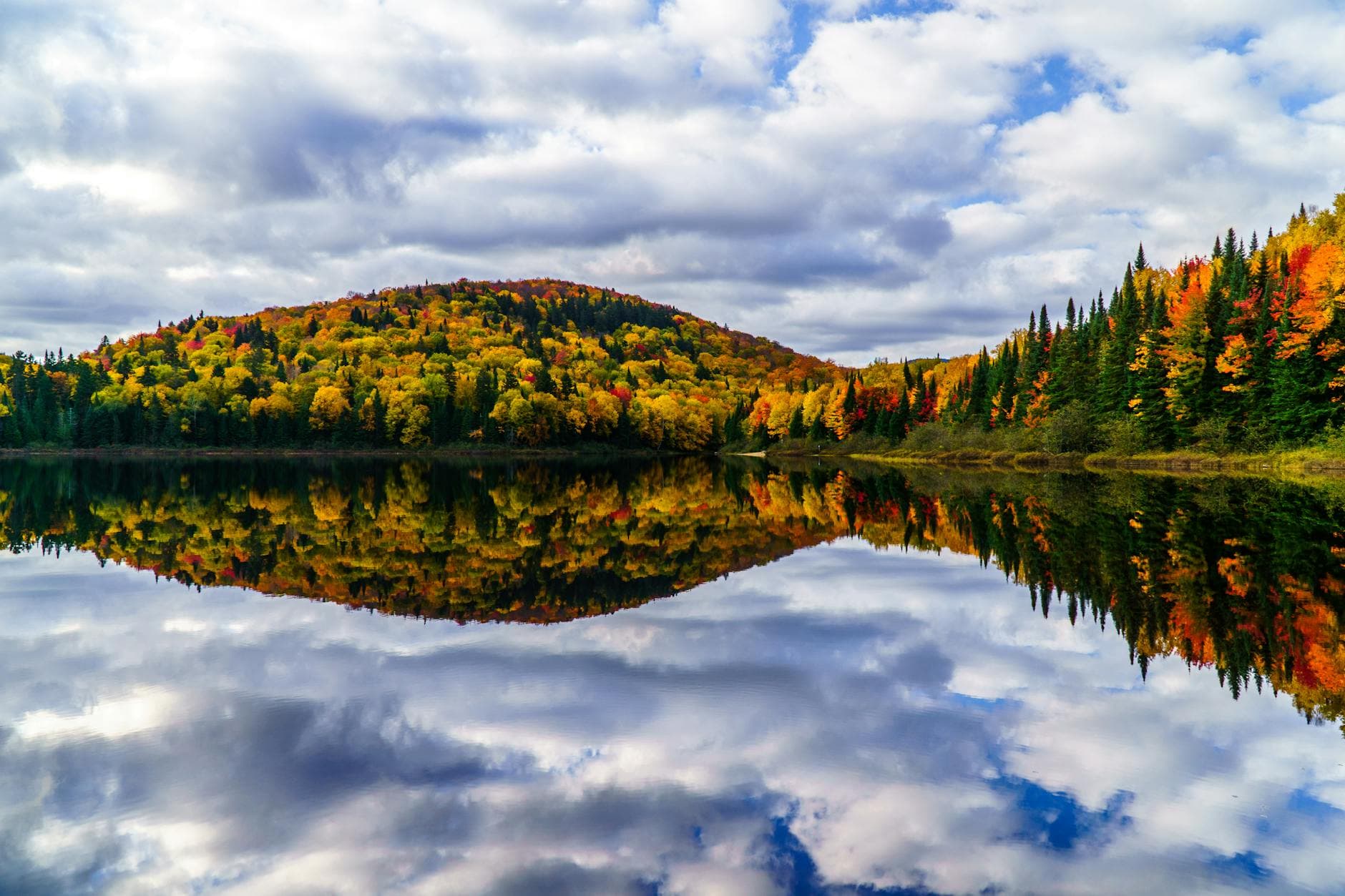 Breathtaking view of autumn foliage reflected in a serene lake in Mont-Tremblant, Canada.