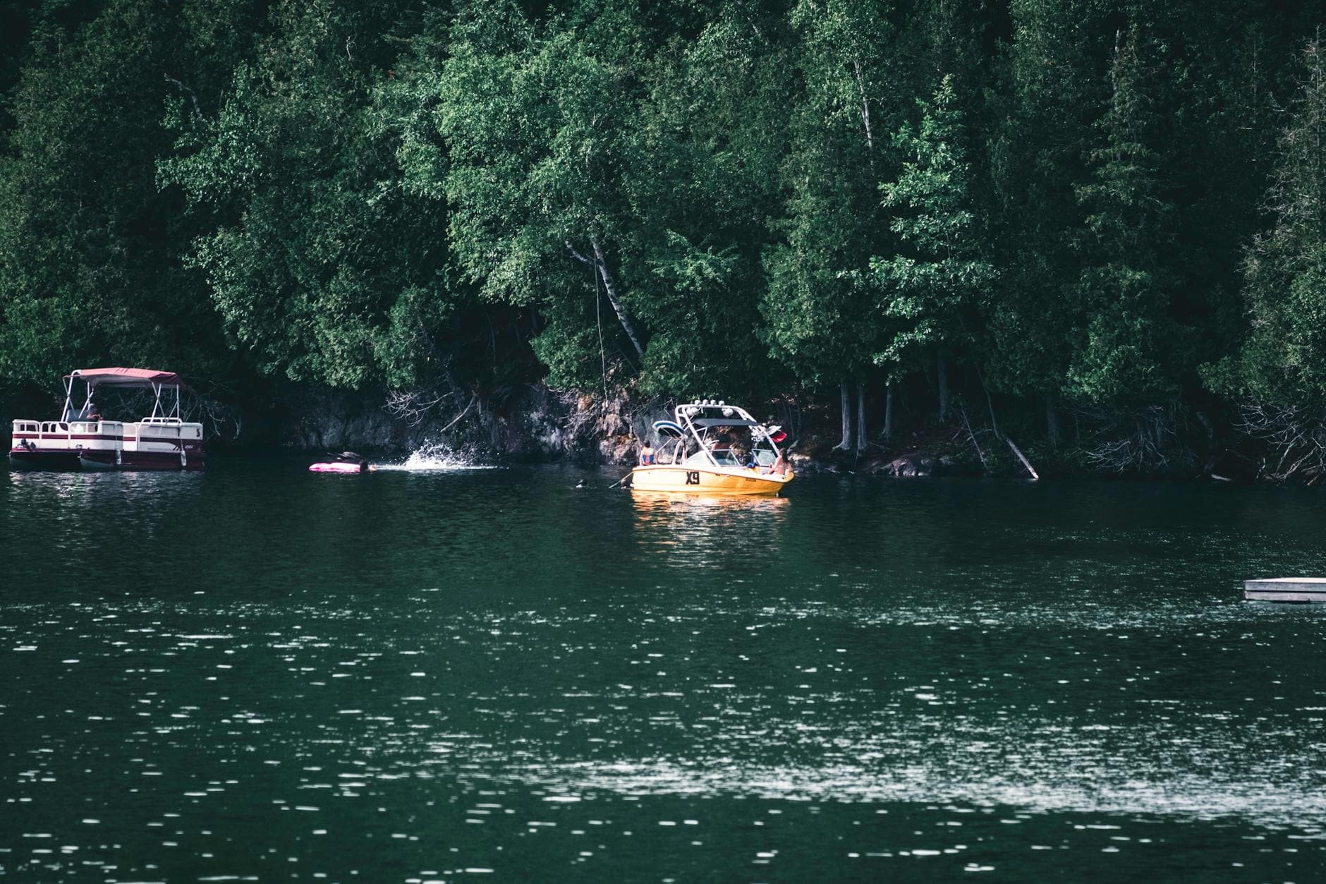 Scenic view of boats on a tranquil lake surrounded by lush greenery in Mont-Tremblant, Canada.