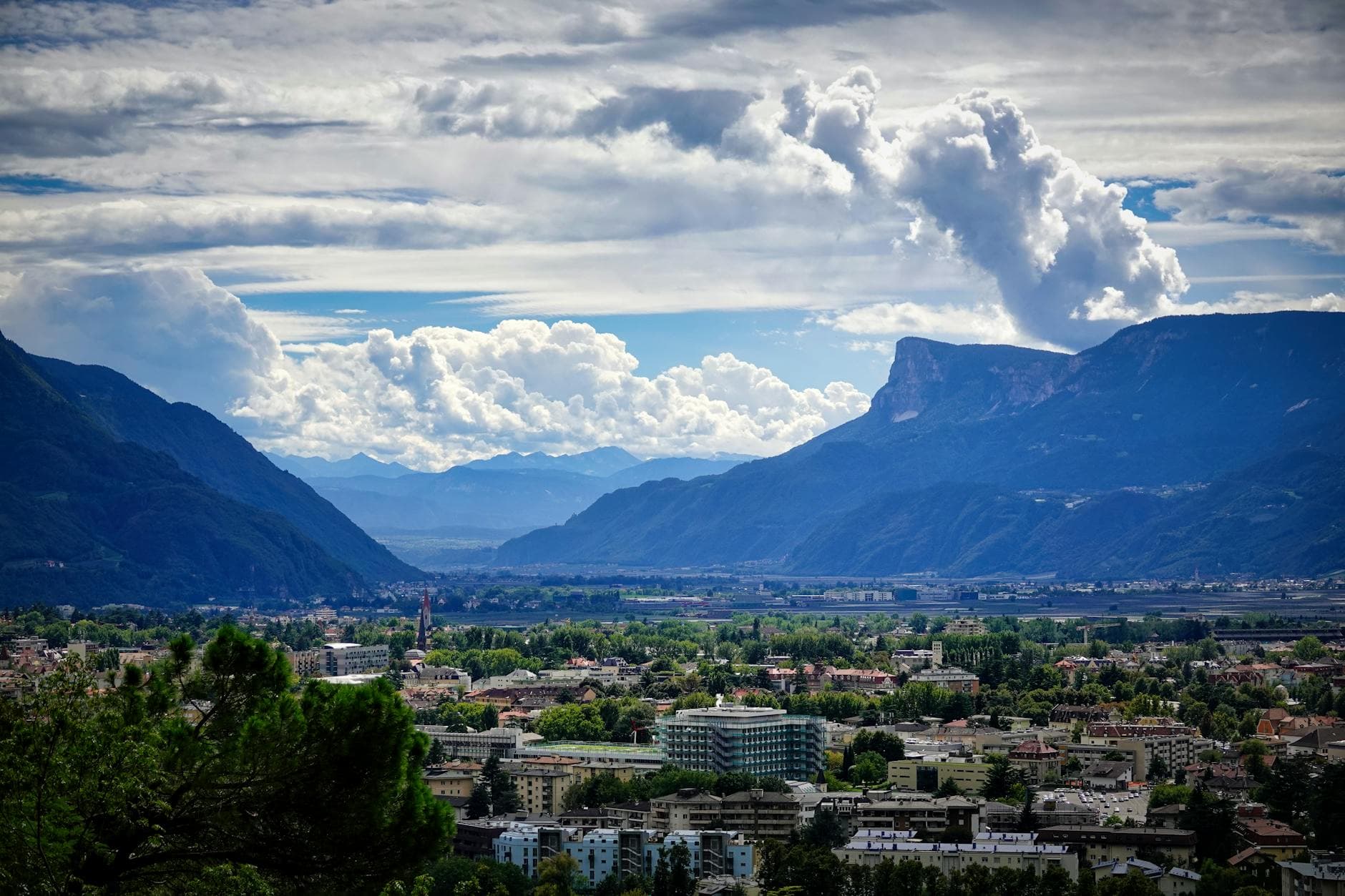A breathtaking aerial view of Meran, Italy, surrounded by lush valleys and towering mountains.