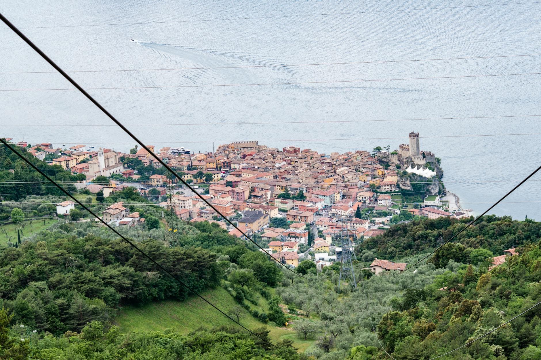 Scenic aerial shot of Malcesine by Lake Garda featuring historic landmarks and lush greenery.