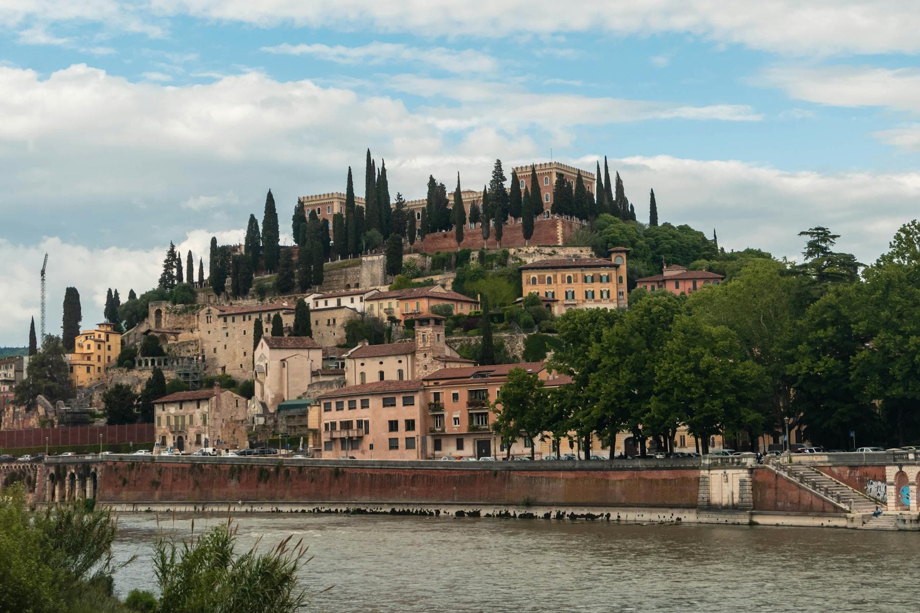 Captivating view of Castel San Pietro on a hill in Verona, featuring historic architecture set amidst lush greenery.