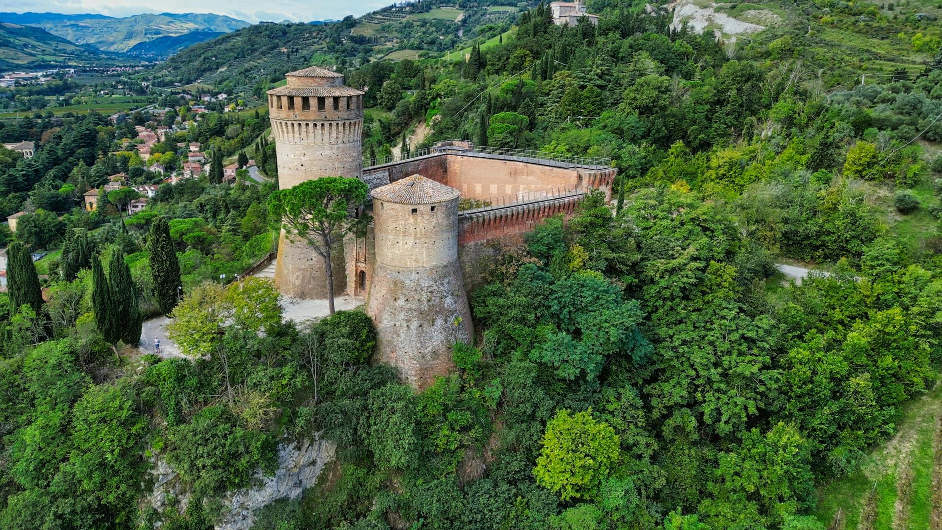 Aerial view of the historic fortress surrounded by lush greenery in Brisighella, Italy.