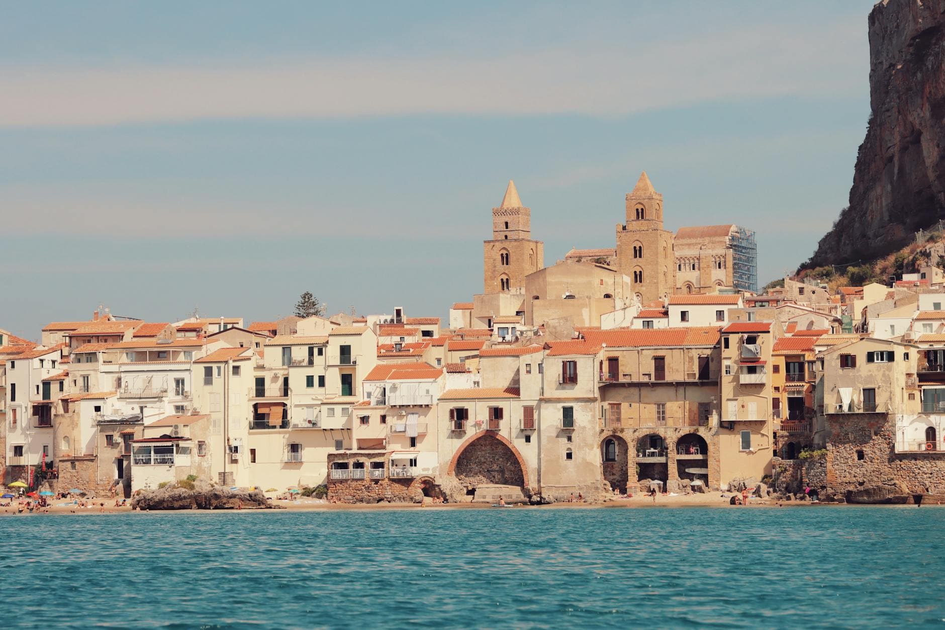 Serene coastal view of Cefalù, Sicily showcasing historic architecture against the blue sea.