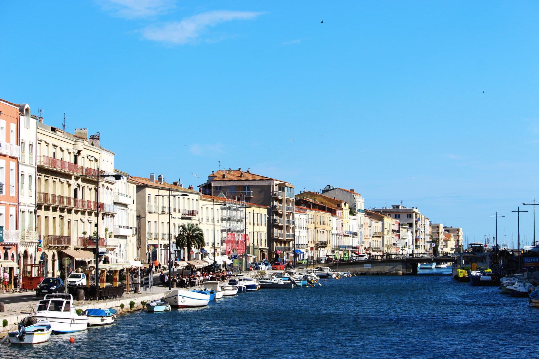 Beautiful waterfront view of a city with boats, vibrant architecture, and a clear blue sky.