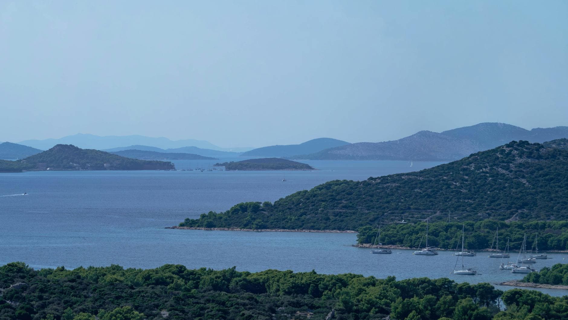 Scenic aerial view of Murter's coastline with yachts moored in the summer blue waters, Croatia.