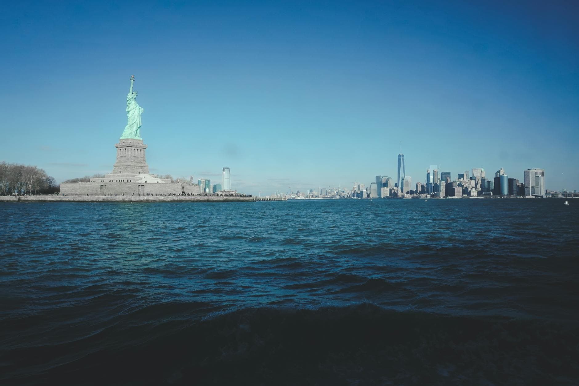 Iconic view of the Statue of Liberty and New York City skyline across the water.
