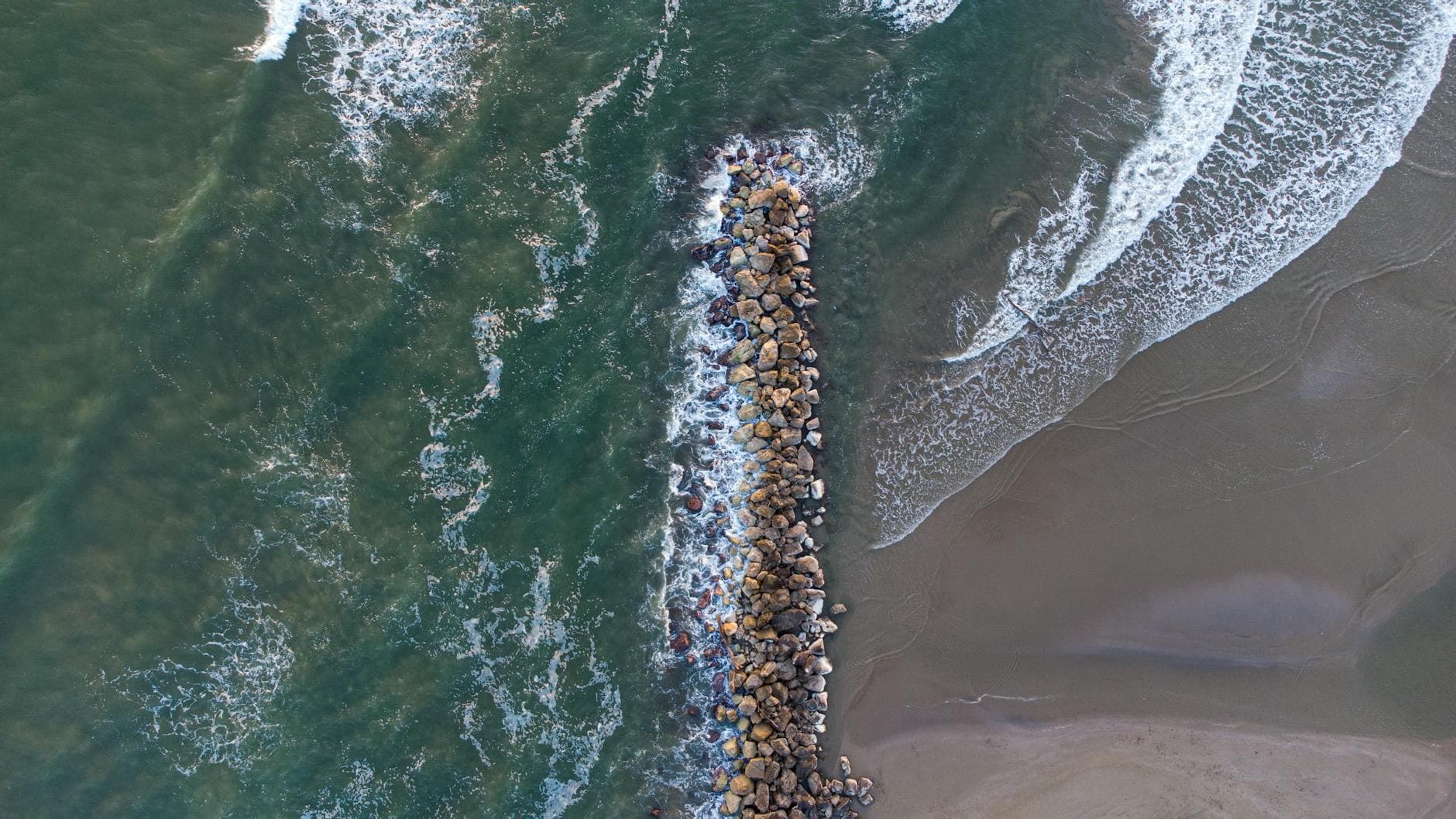 Drone shot of rocks and waves at Nettuno beach, Lazio, Italy.