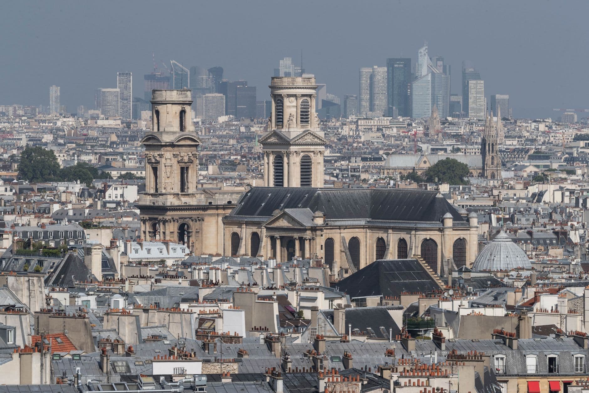 A panoramic view of Paris featuring the Saint-Sulpice church with a backdrop of modern skyscrapers.