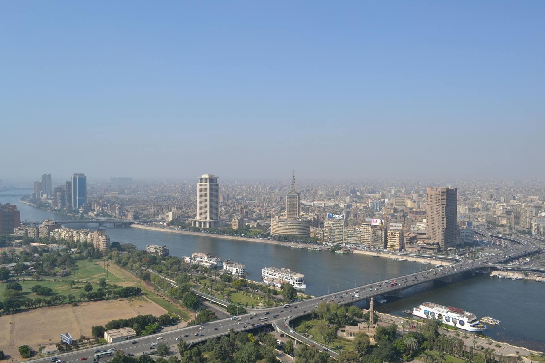 Aerial view of downtown Cairo with Nile River and urban skyline showcasing landmarks and busy traffic.