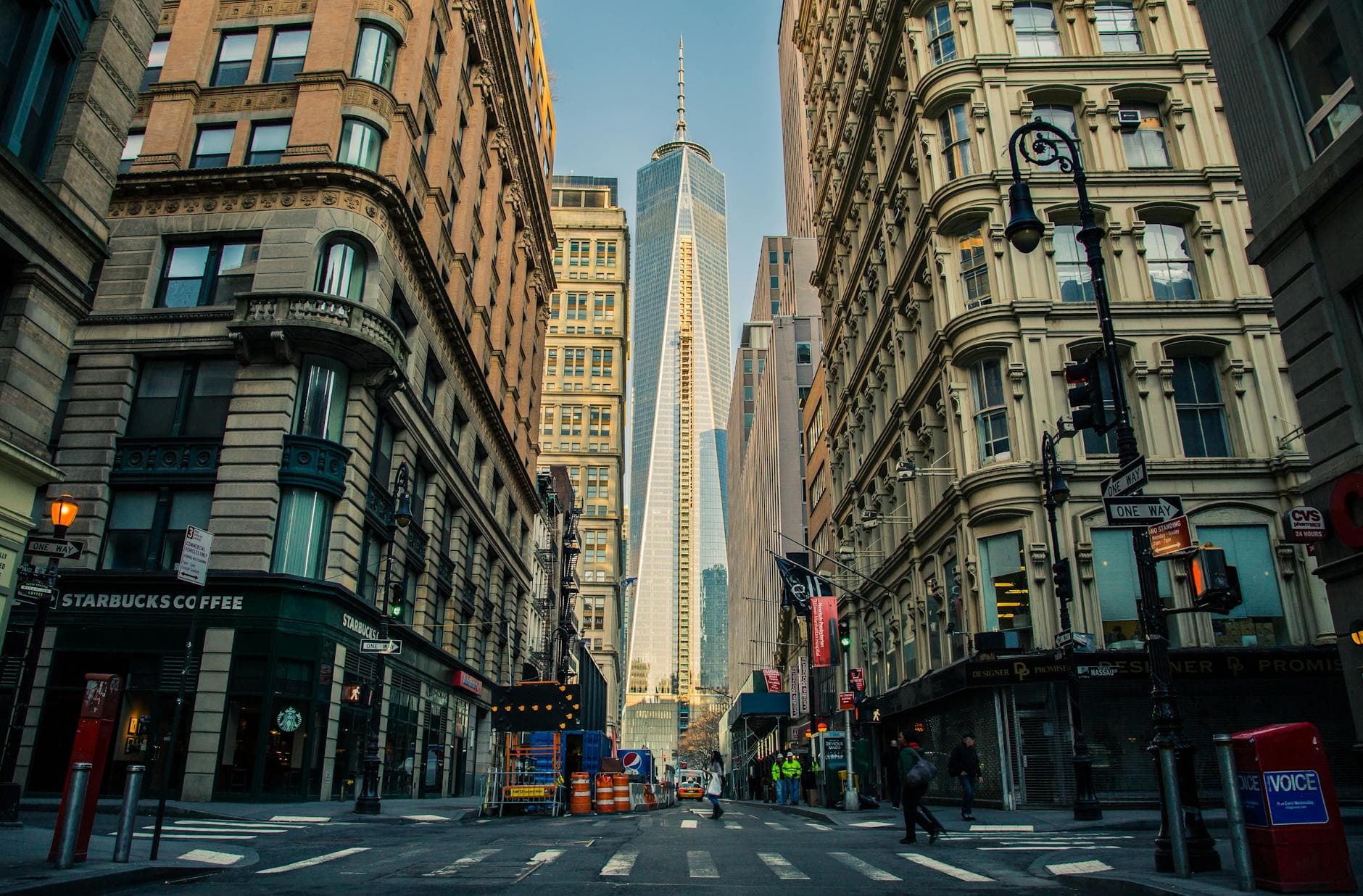 Street view of One World Trade Center in New York City surrounded by urban architecture and city life.