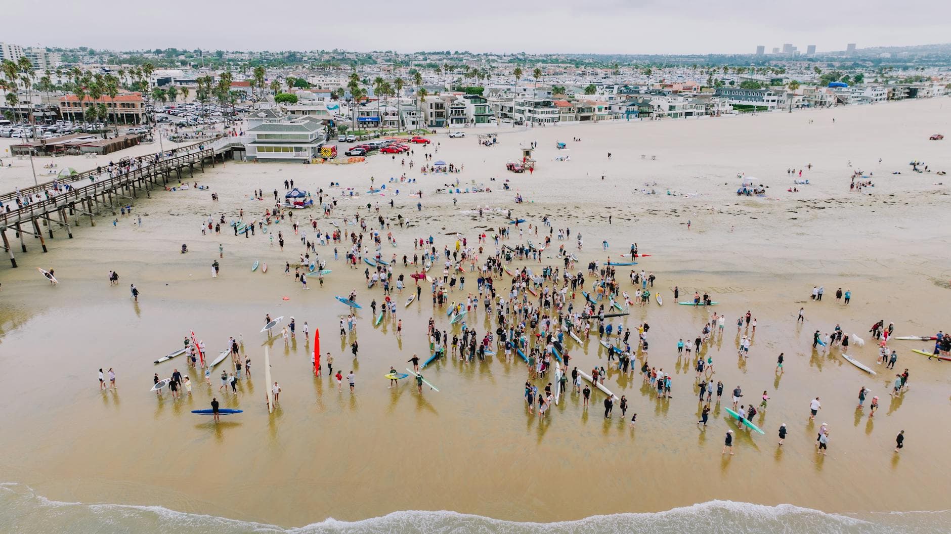 A vibrant aerial shot of surfers gathered at Newport Beach, California, showcasing community and coastal lifestyle.