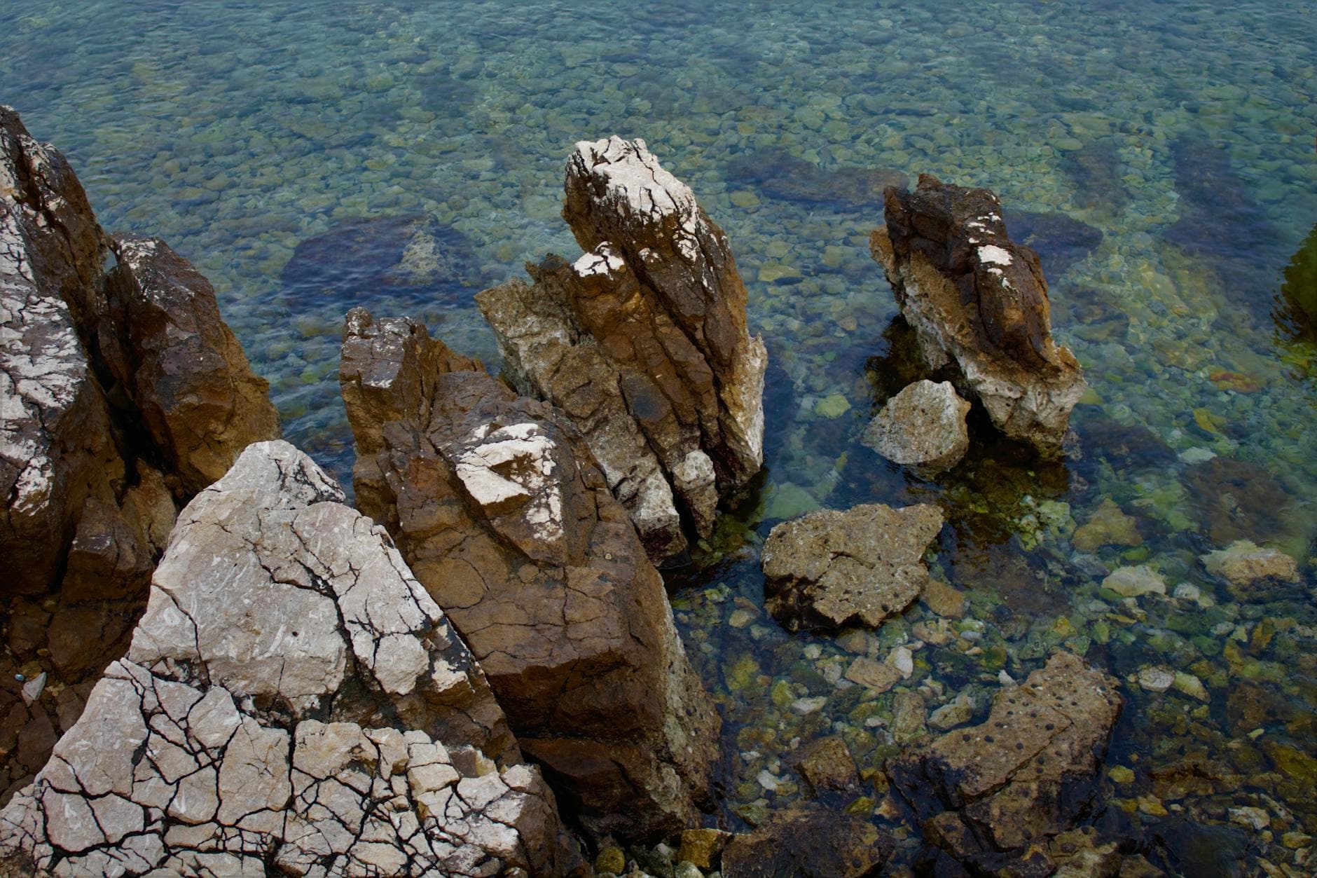 A scenic view of the rocky coastline with clear turquoise waters in Njivice, Croatia.