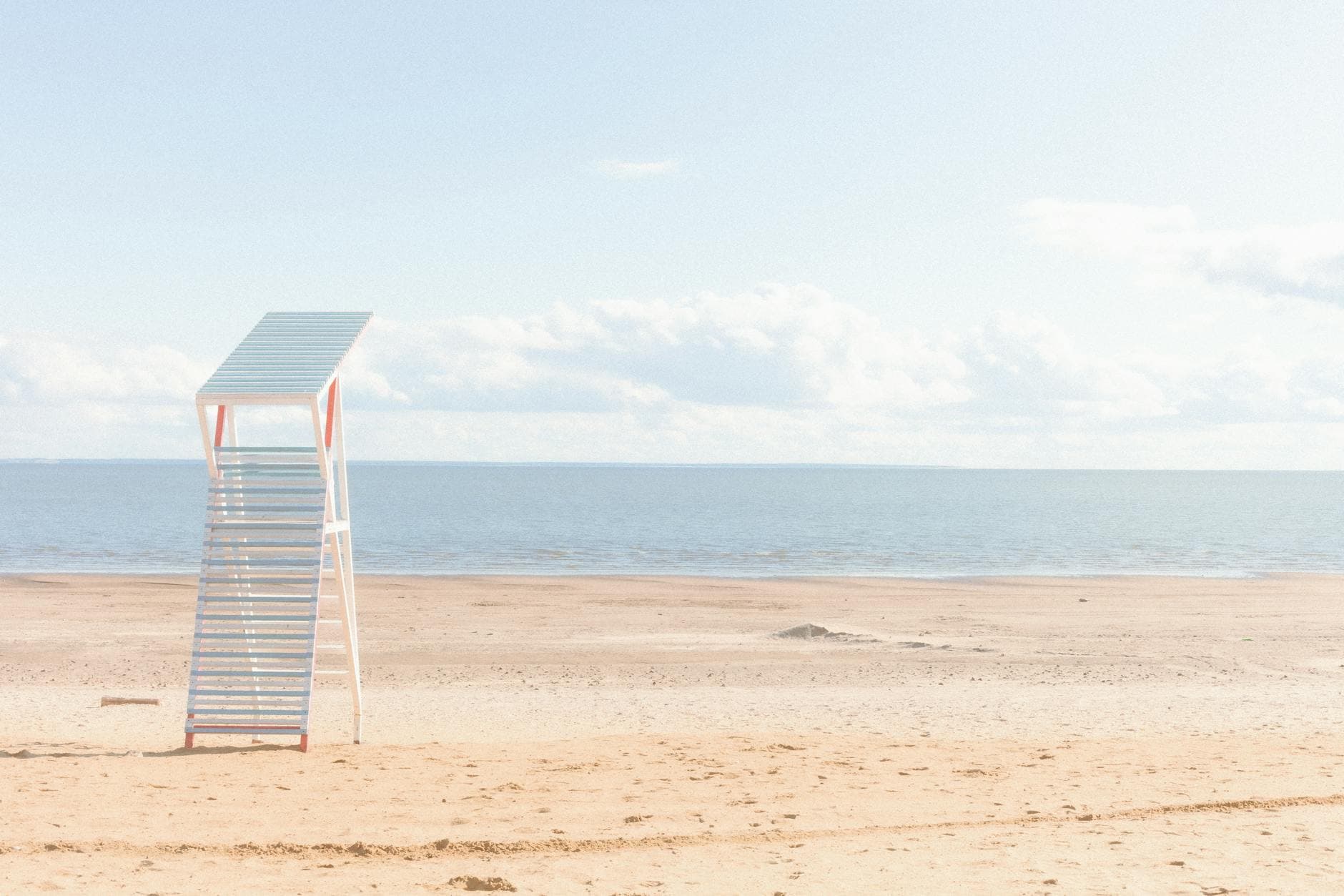 A serene and minimalistic beach scene featuring a lifeguard tower by the calm ocean.