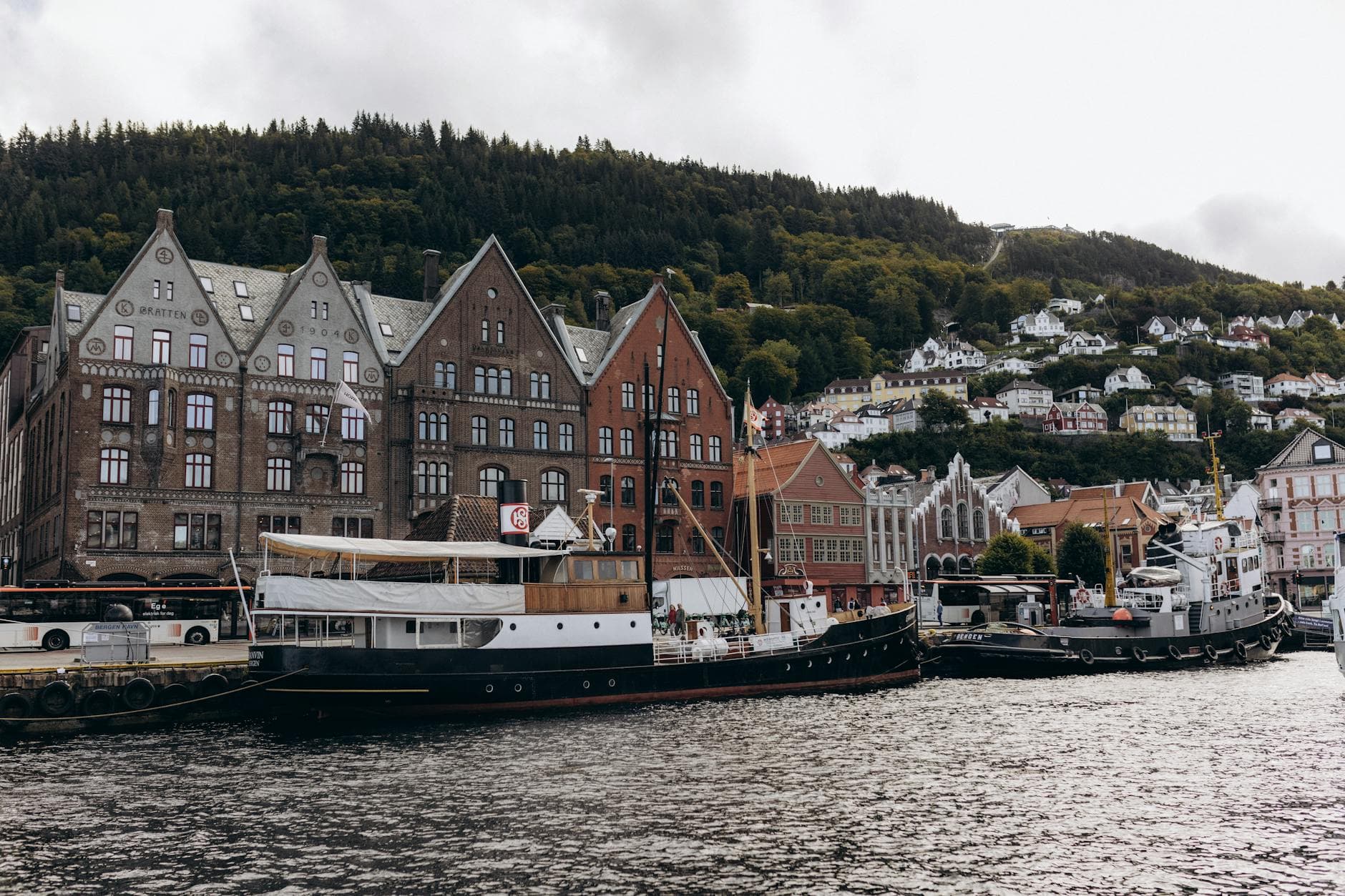 Scenic view of Bryggen's historic wharf with boats in Bergen, Norway on a cloudy day.