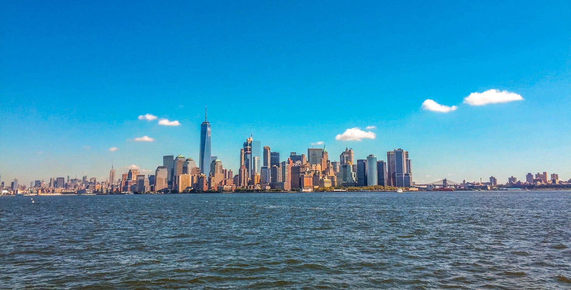 Stunning view of New York City skyline with blue skies from the waterfront.