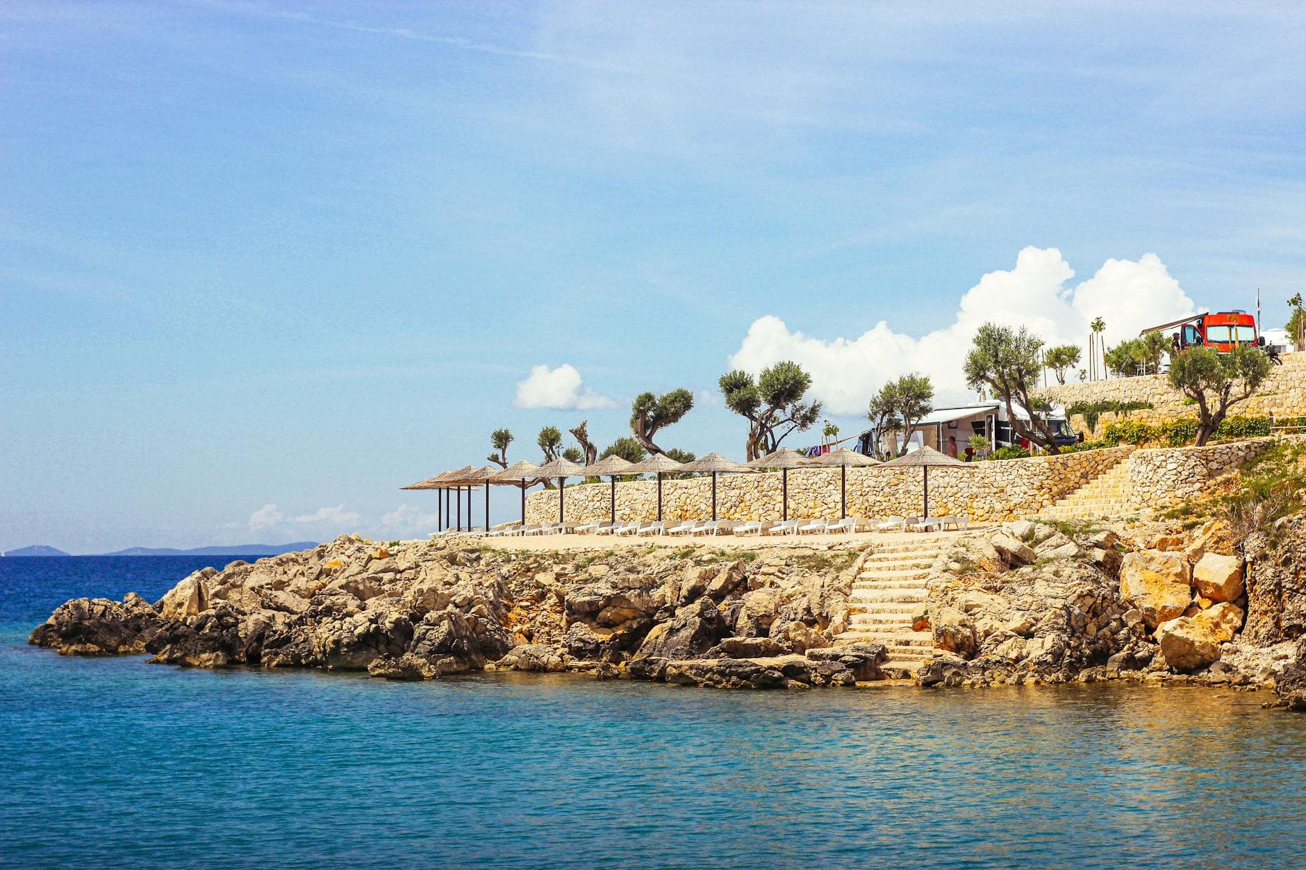 Beautiful rocky coastline with clear blue water in Novalja, Croatia under a bright sky.