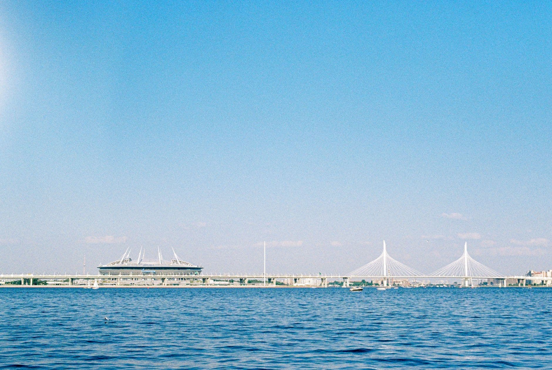 Stunning view of a modern bridge and stadium by the waterfront under a clear blue sky.