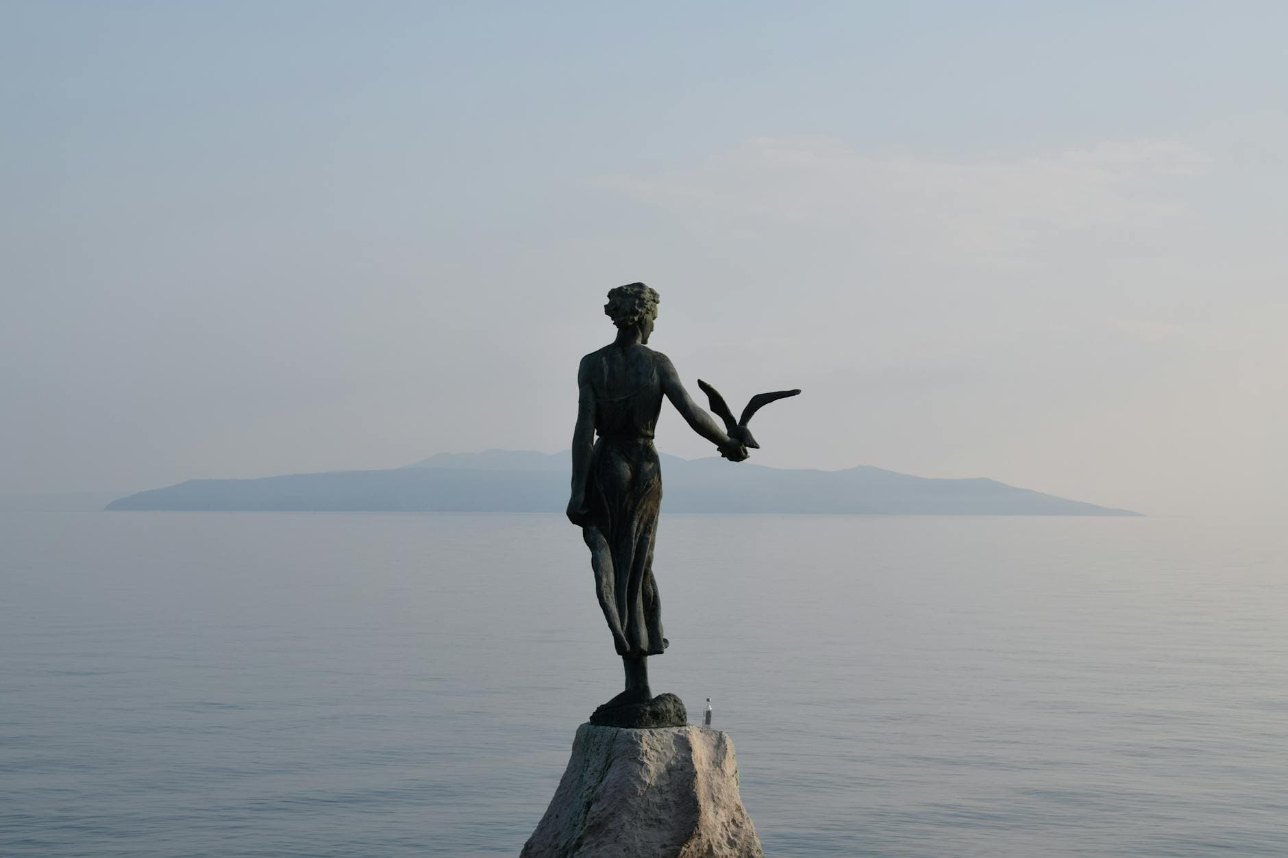 Serene view of the Woman with a Seagull statue against the Adriatic Sea in Opatija, Croatia.
