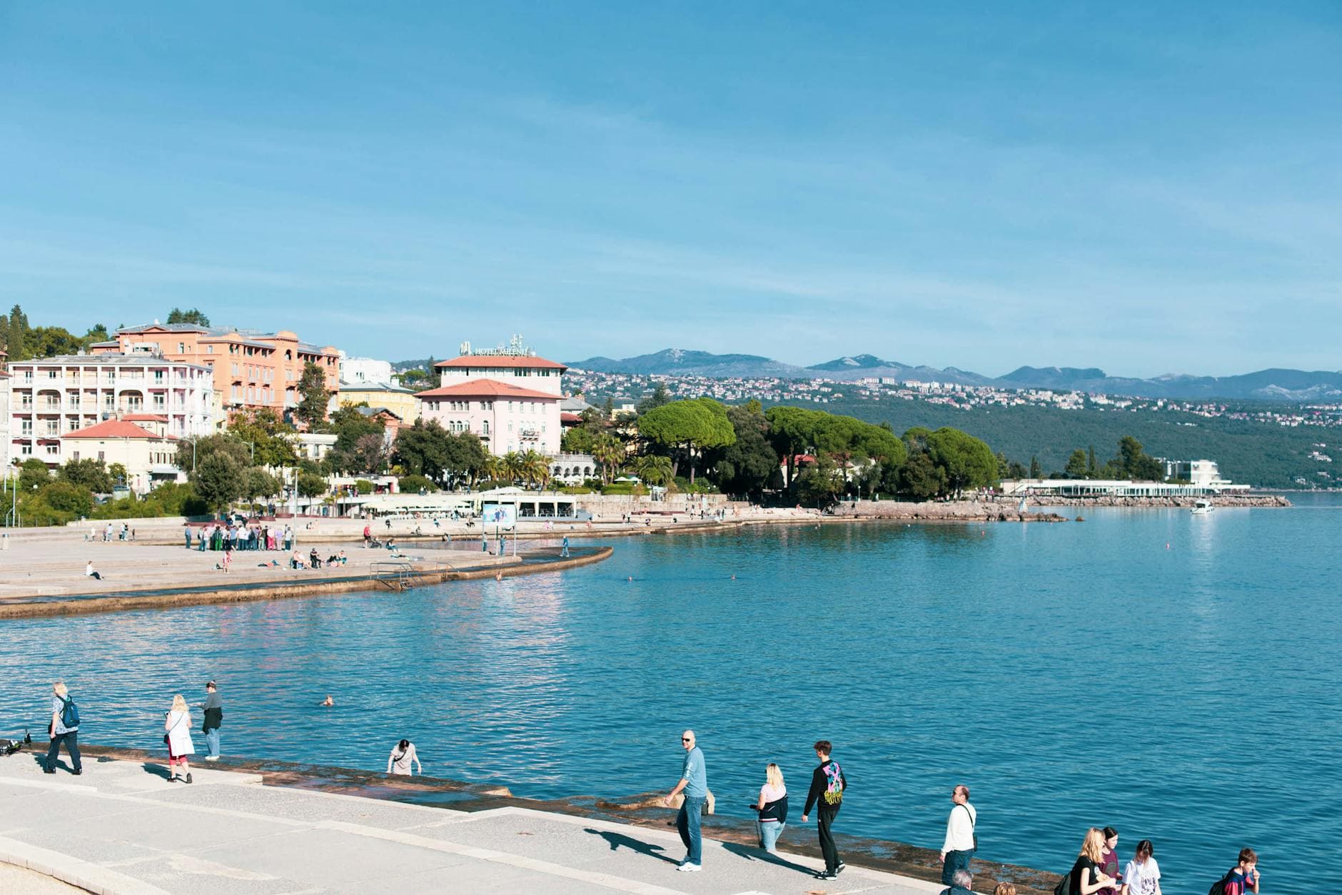 Sunny day in Opatija, Croatia, with people strolling by the Adriatic Sea.
