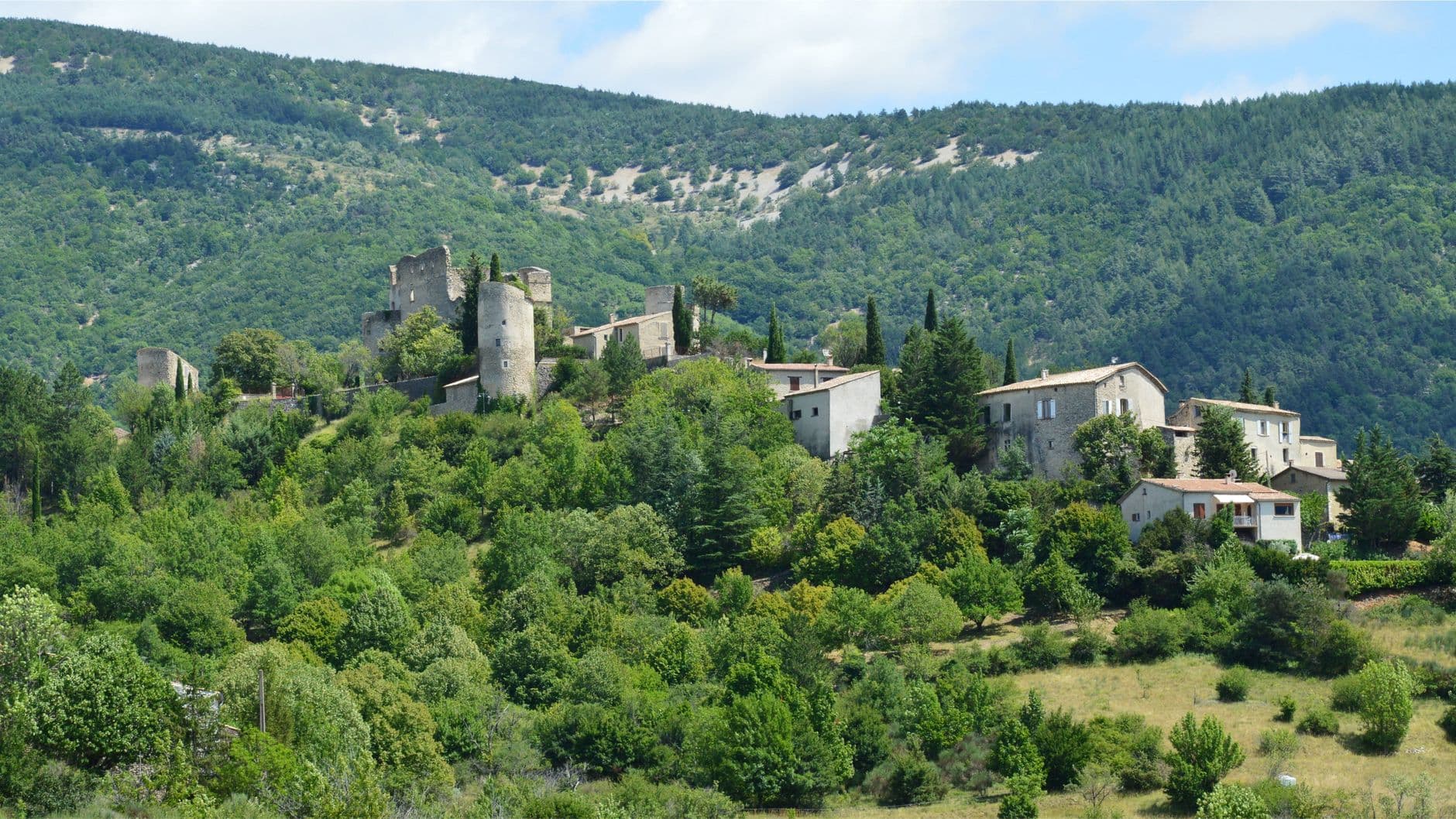 Picturesque view of a mountain village and old castle surrounded by lush greenery.