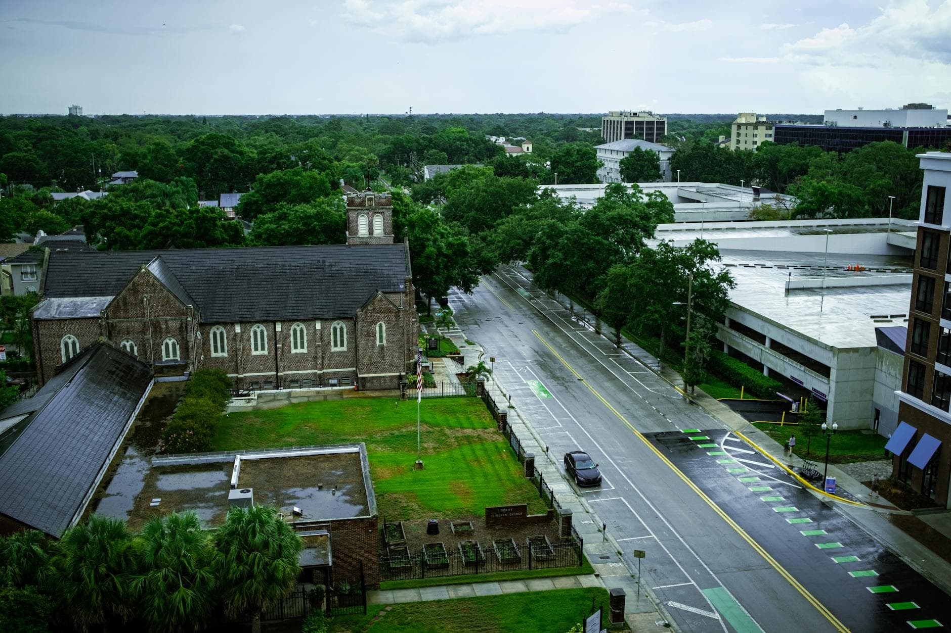 Aerial view of Orlando's wet streets and greenery after rain, featuring historic building.