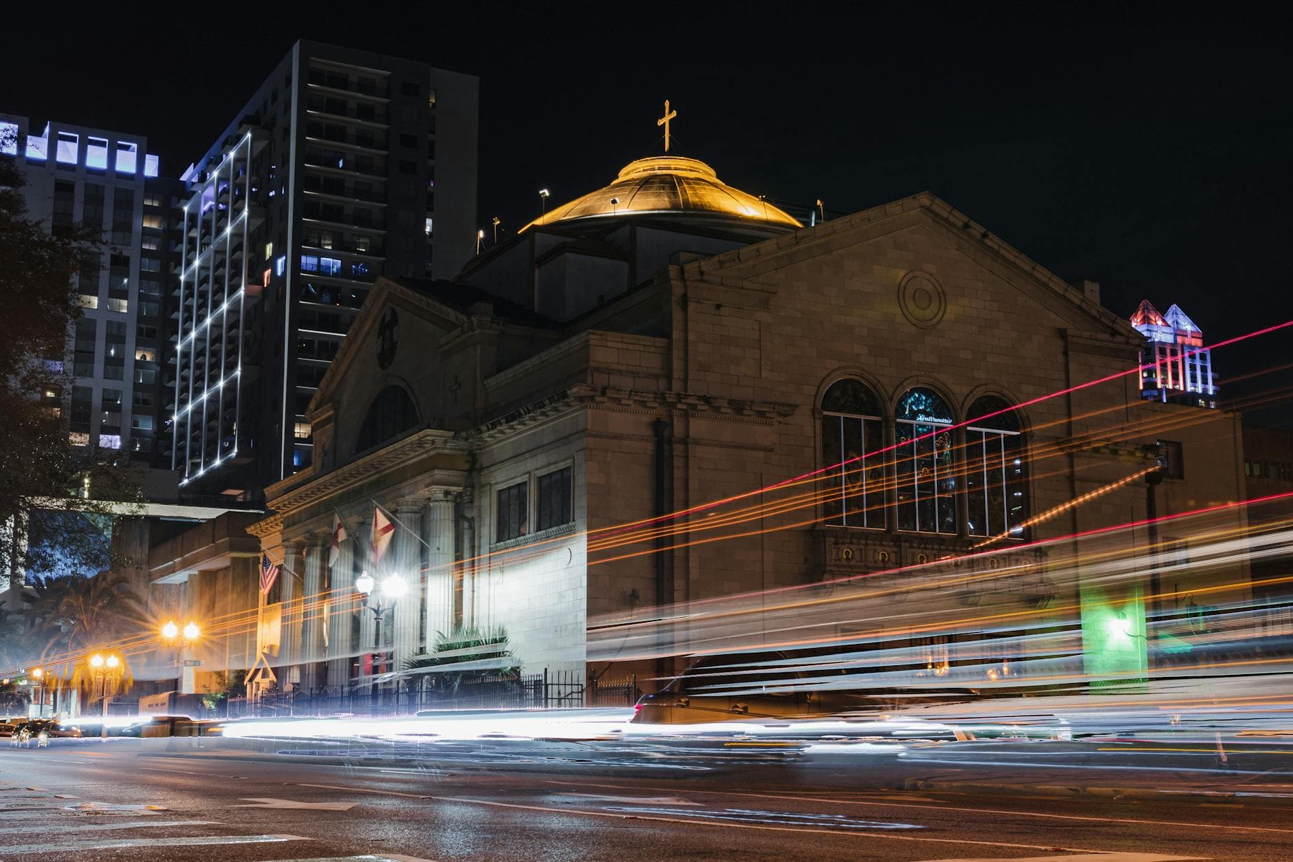 A stunning night view of a church in downtown Orlando with vibrant light trails from passing cars, highlighting urban life.