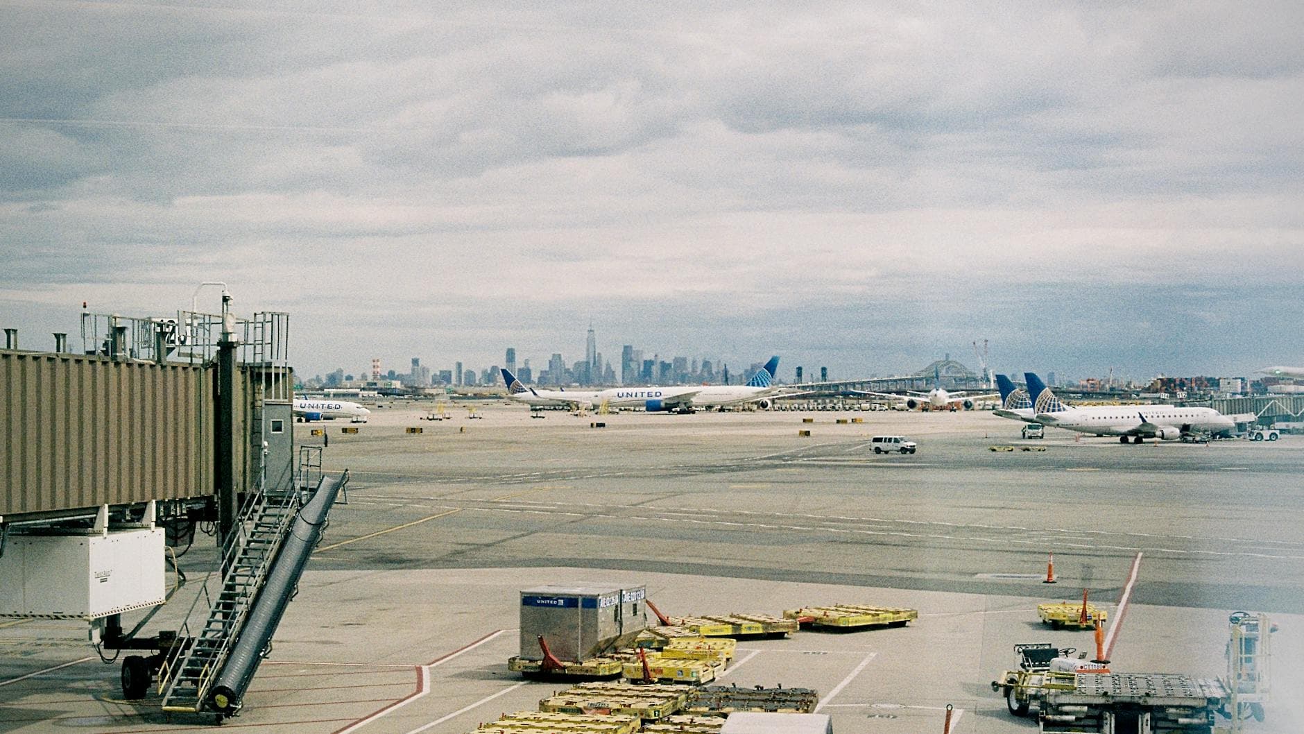 Aircraft waiting on JFK airport apron with New York City skyline in the background.