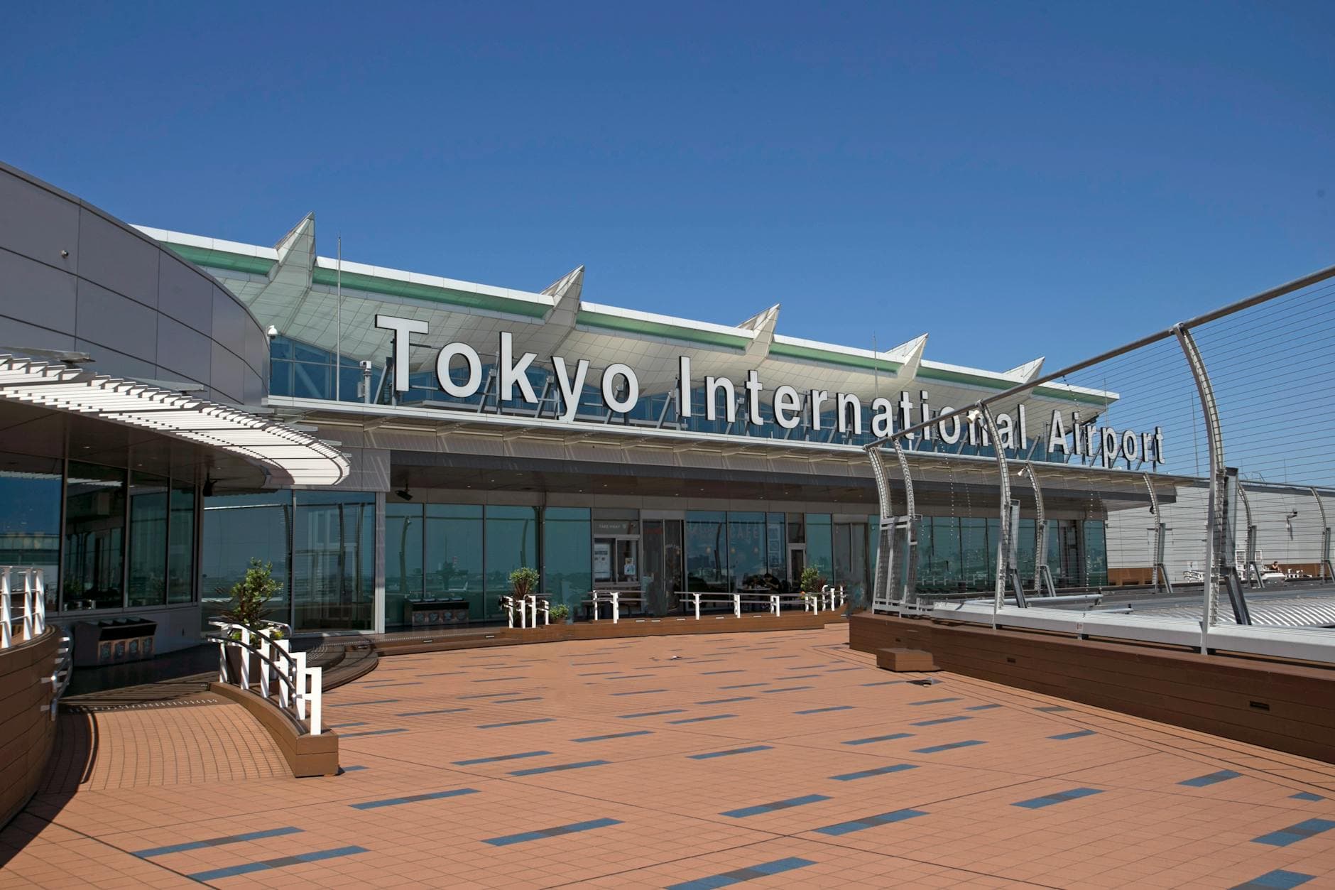 A sunny day view of Tokyo International Airport's entrance with clear blue skies.