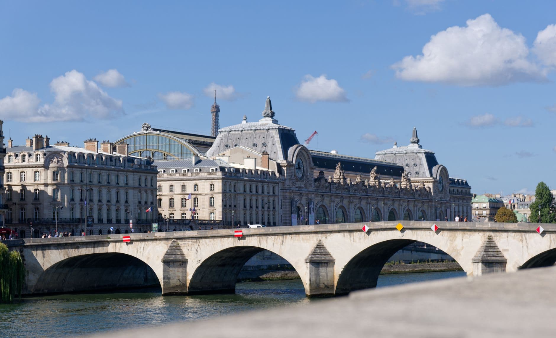 Scenic view of Pont Royal in Paris with the Musée d'Orsay and Eiffel Tower under a clear blue sky.