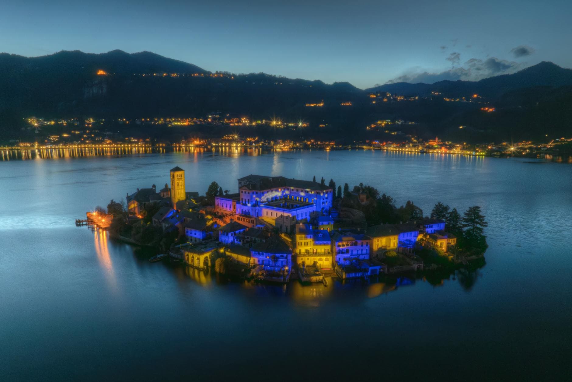 Aerial view of San Giulio Island at twilight, beautifully illuminated over Lake Orta in Italy.