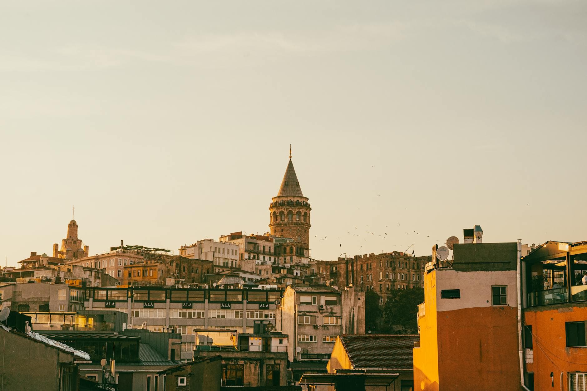 View of the historic Galata Tower amidst the Istanbul skyline during a warm sunset.